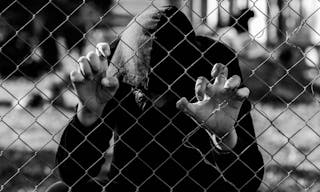 Young unidentifiable teenage boy holding the wired garden at the correctional institute in black and white, conceptual image of 