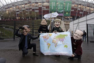 Protesters wearing masks of world leaders hold a map and a sign on the last day of U.N. climate talks in Warsaw