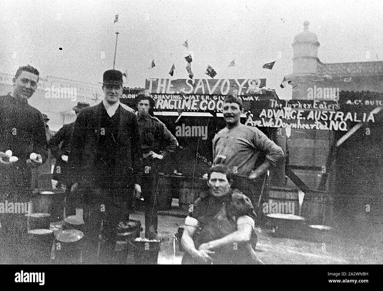 Negative - Cooks at the Army Camp, Royal Park, Victoria, World War I, Aug 1916, Cooks at the army camp. Signs on the structure in the background read: 'The Savoy','Shaving water given away','Ragtime cook' and 'Advance Australia Stock Photo