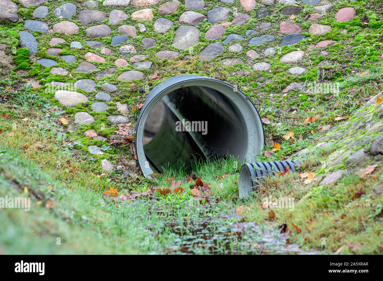 Drainage pipe. Culvert under small road. Drainage ditch and pipes in the city Stock Photo