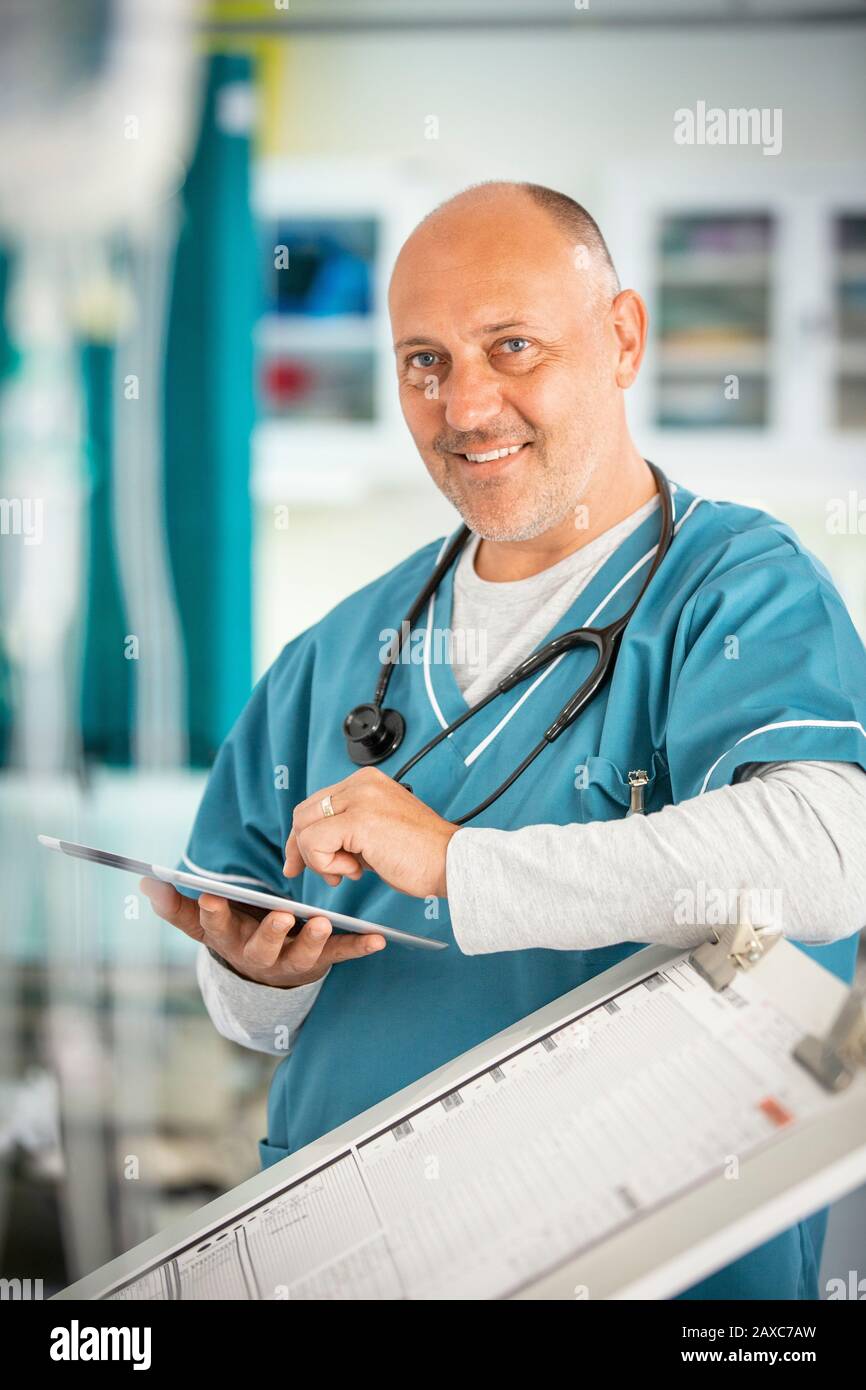 Portrait smiling, confident male doctor using digital tablet in hospital Stock Photo