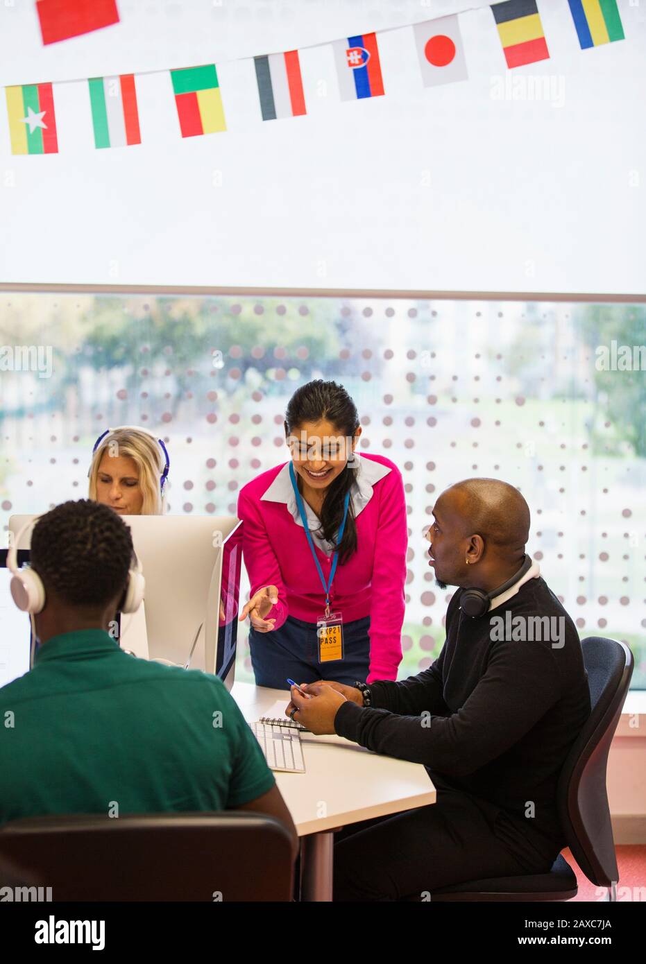 Community college instructor helping students using computers in computer lab Stock Photo