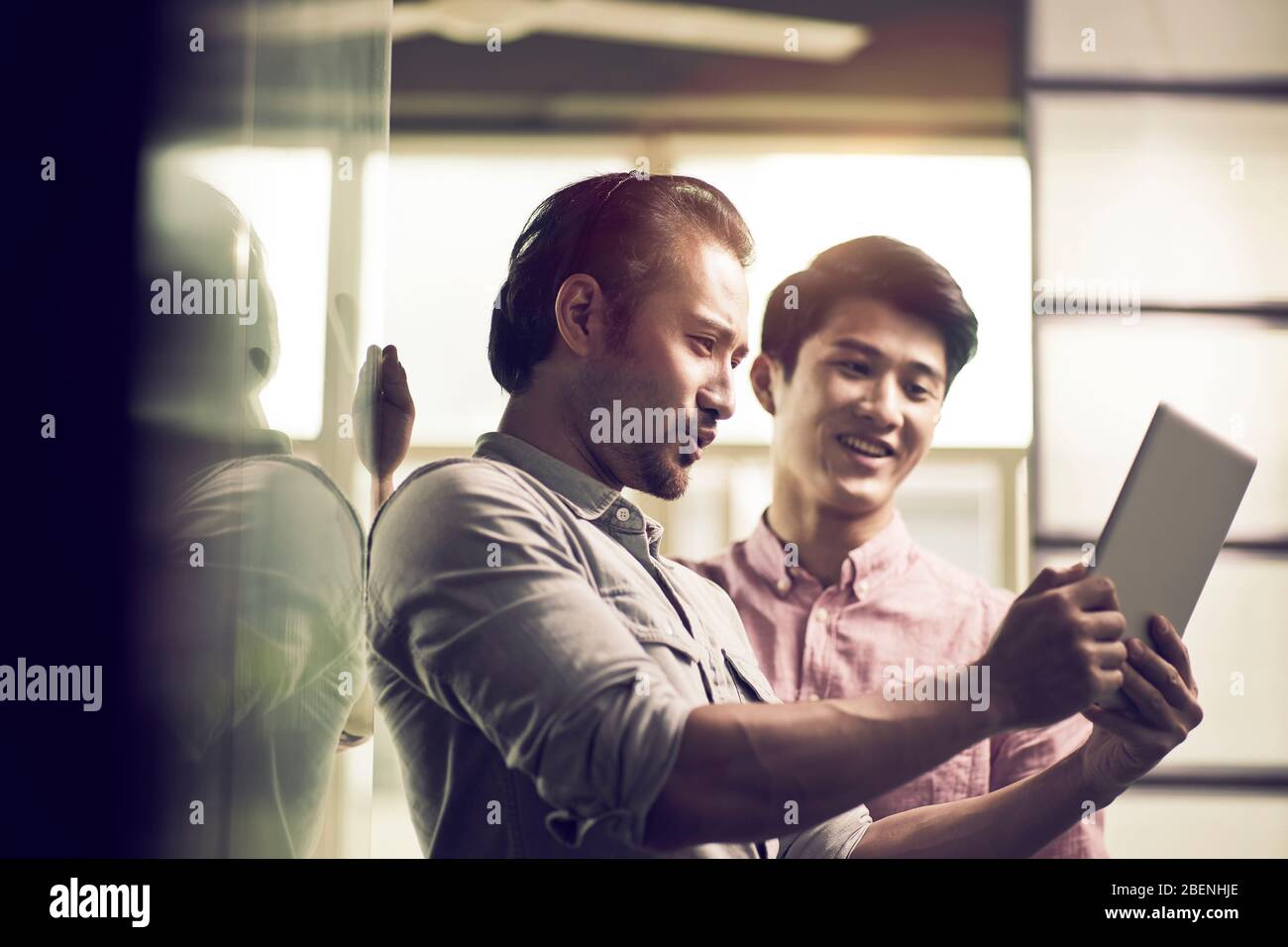 two asian businessmen working together in office looking at digital tablet Stock Photo