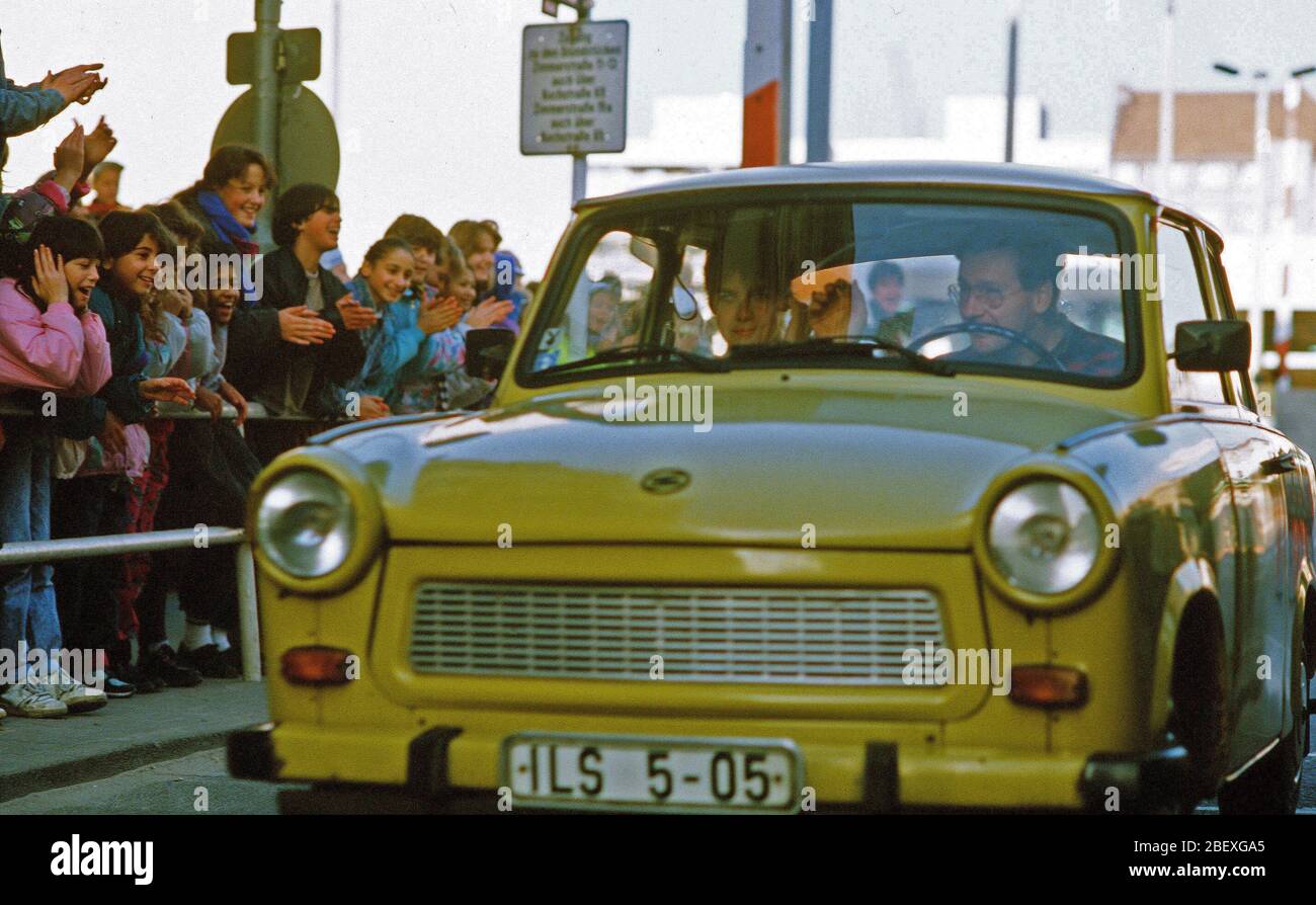 West German children applaud as an East German couple drive through Checkpoint Charlie and take advantage of relaxed travel restrictions to visit West Germany. Stock Photo