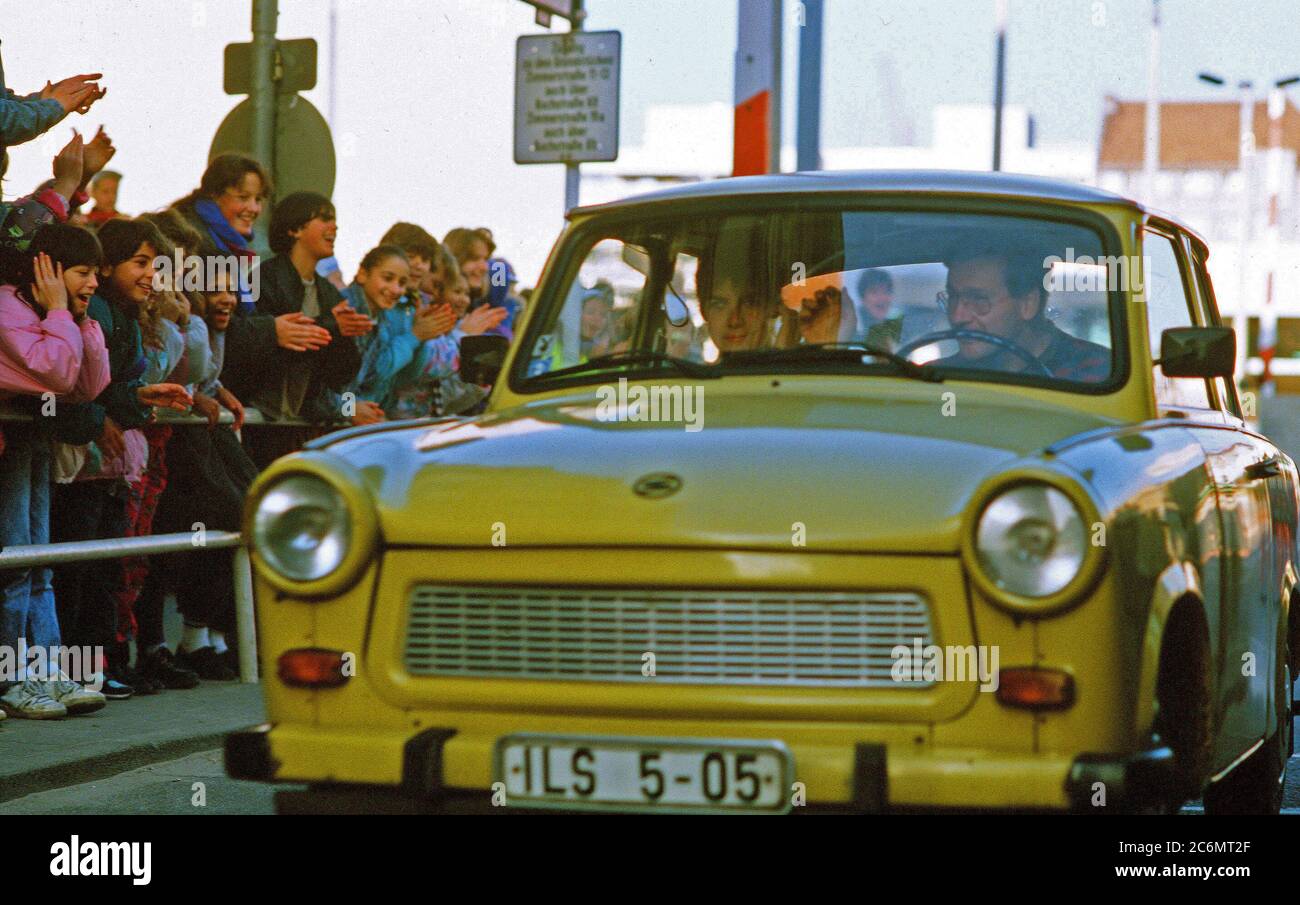 West German children applaud as an East German couple drive through Checkpoint Charlie and take advantage of relaxed travel restrictions to visit West Germany. Stock Photo