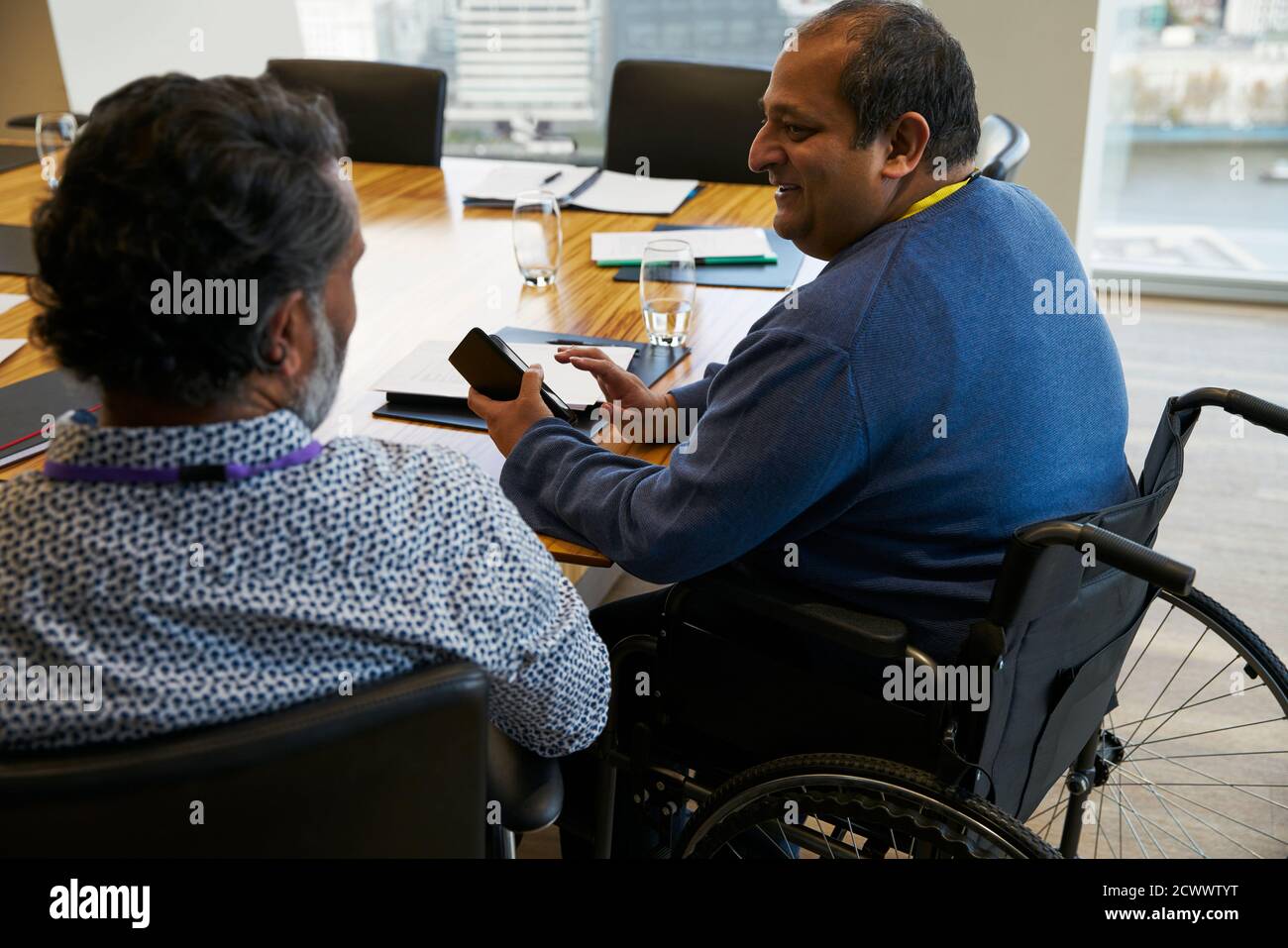 Businessman in wheelchair talking with colleague in meeting Stock Photo