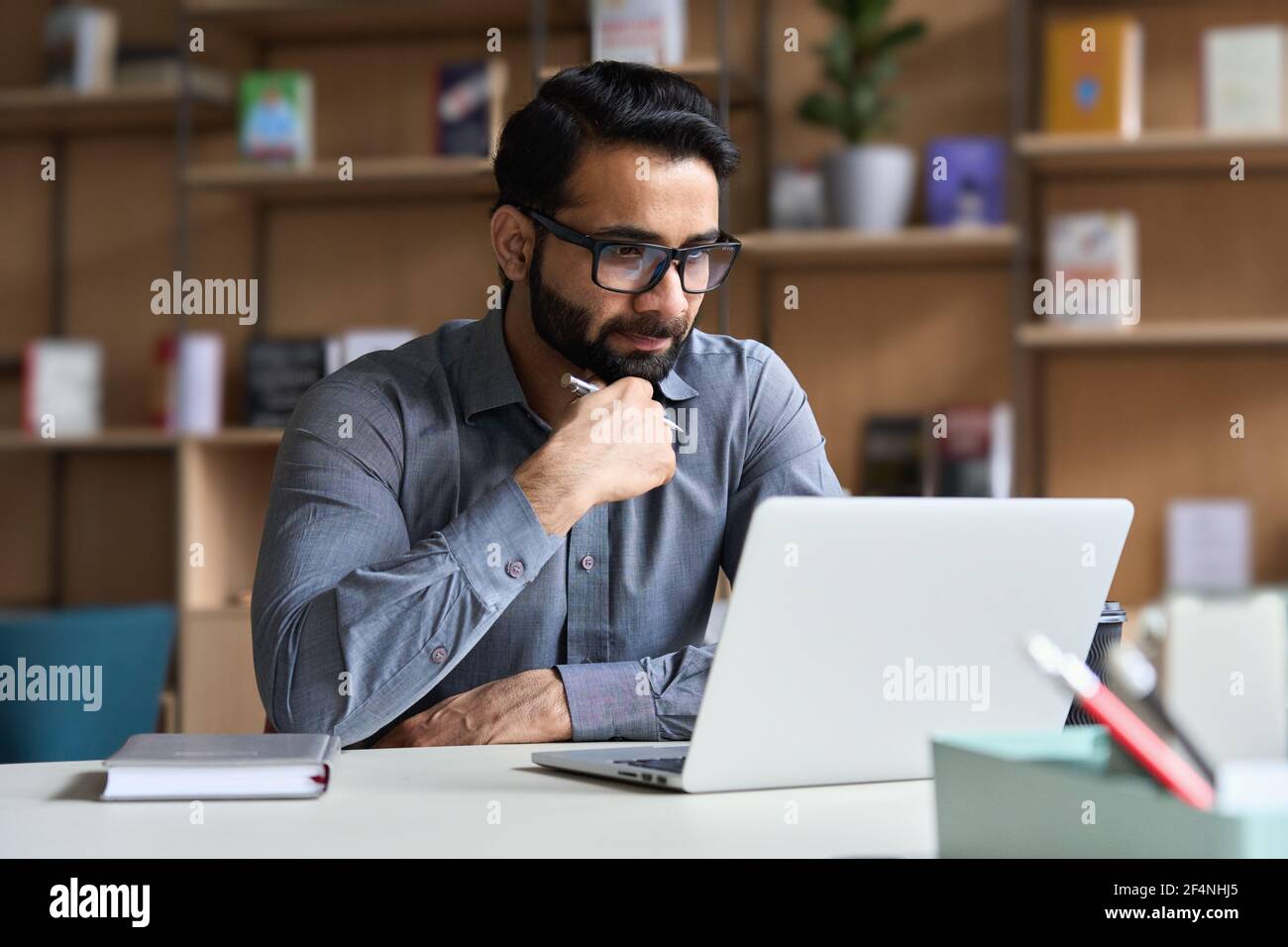 Serious indian business man working or studying on laptop computer. Stock Photo