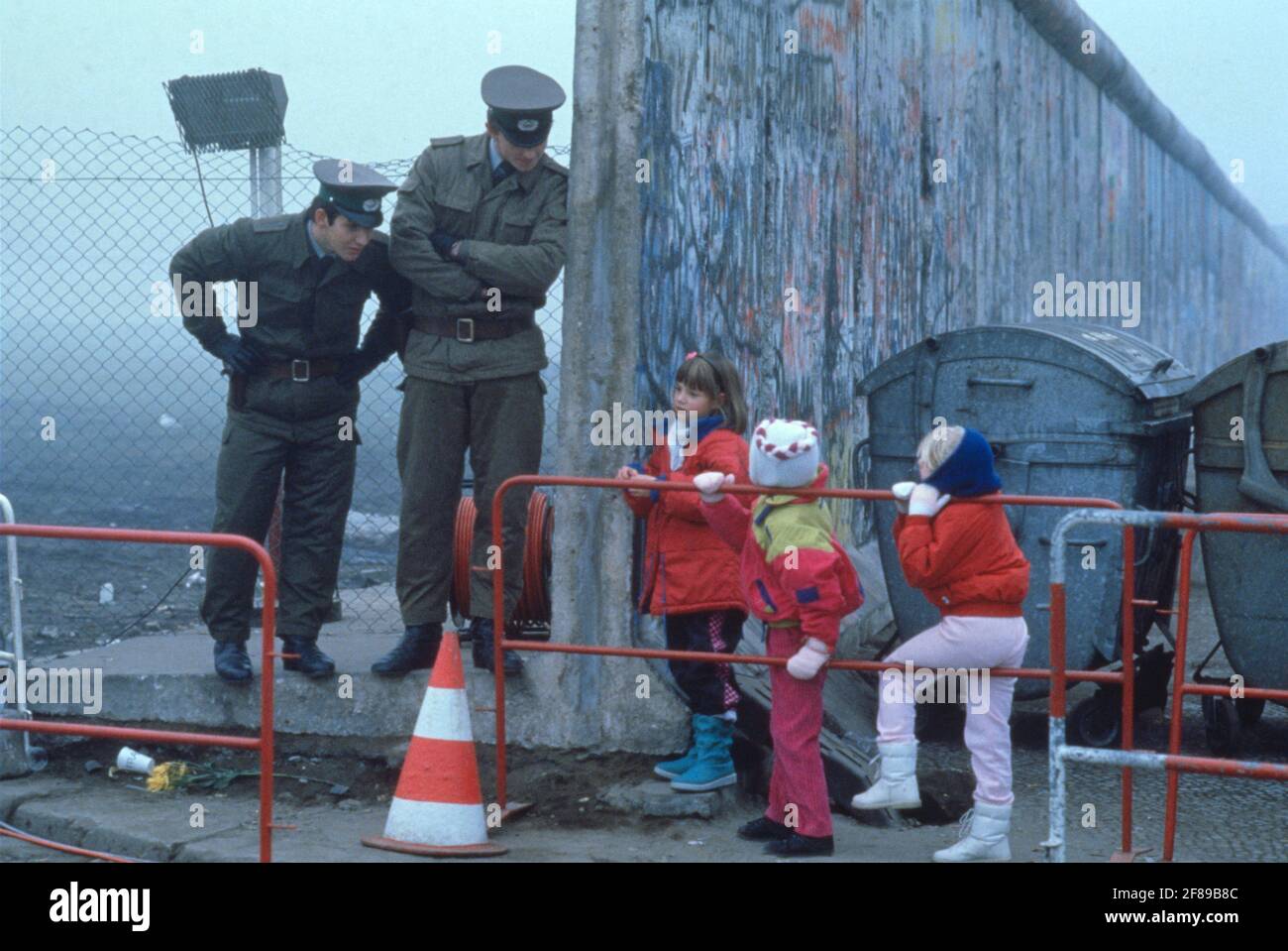 East German guards talk to West Berlin children on their way to school after the reunification November 1989 Stock Photo