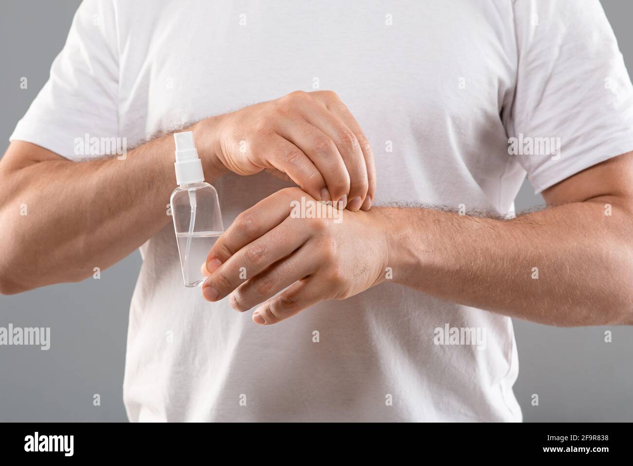 Unrecognizable man holding spray, scratching his hand Stock Photo