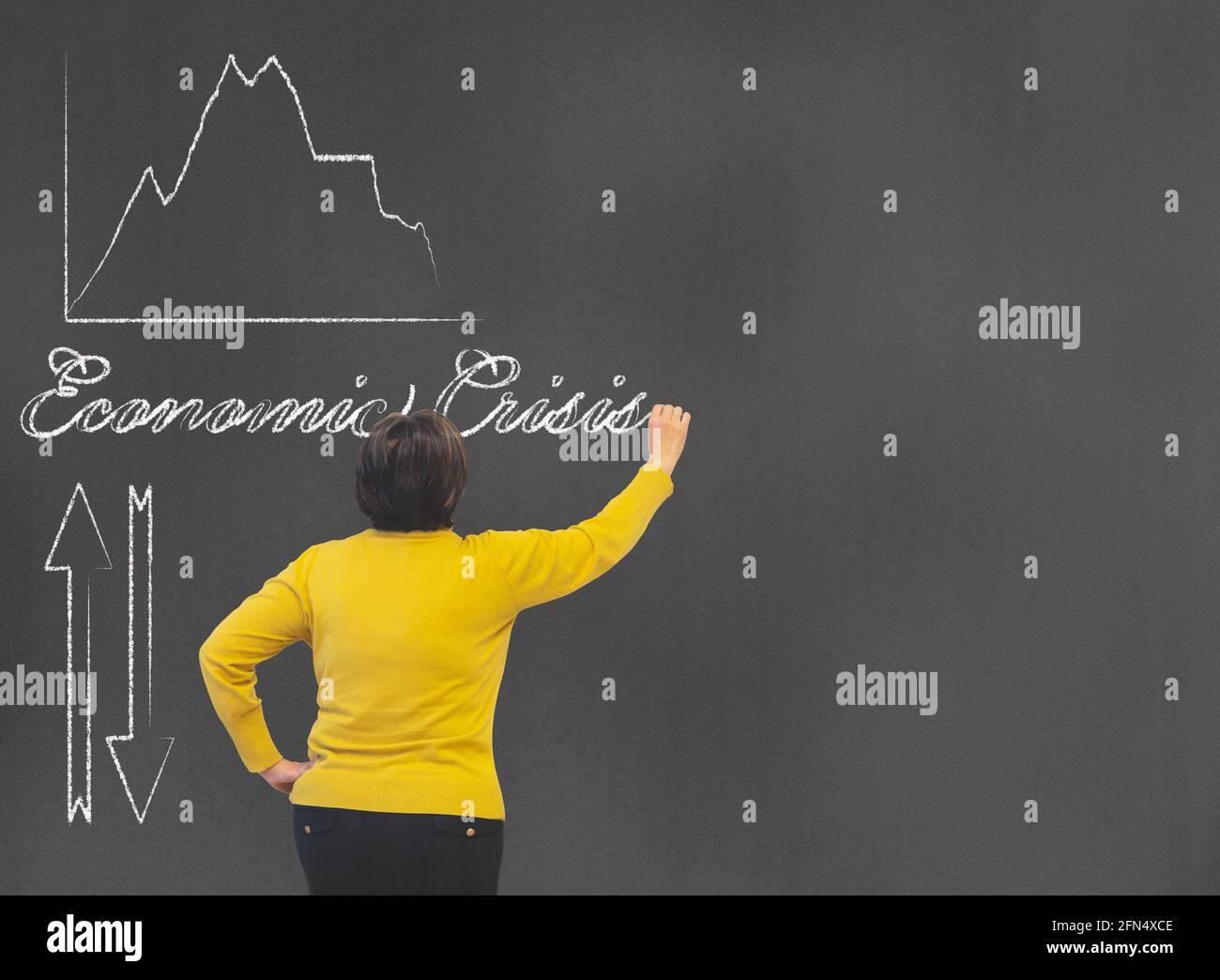 Middle-aged woman writing on the blackboard with a chalk the concepts of economic crisis with arrows and financial diagram with copy space concept eco Stock Photo