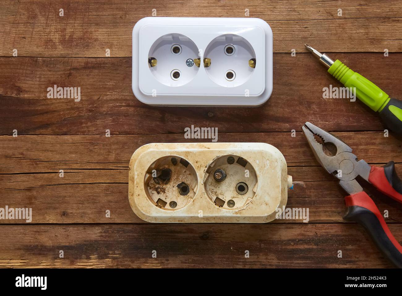 Burnt out electrical outlet and new to replace on a wooden background Stock Photo