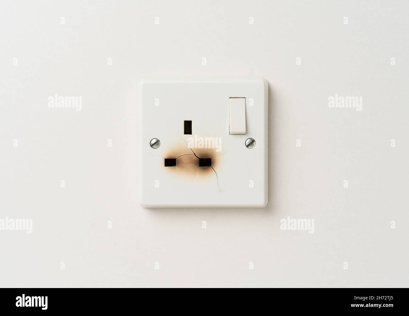 Damaged electrical domestic power socket with cracks and burn marks Stock Photo