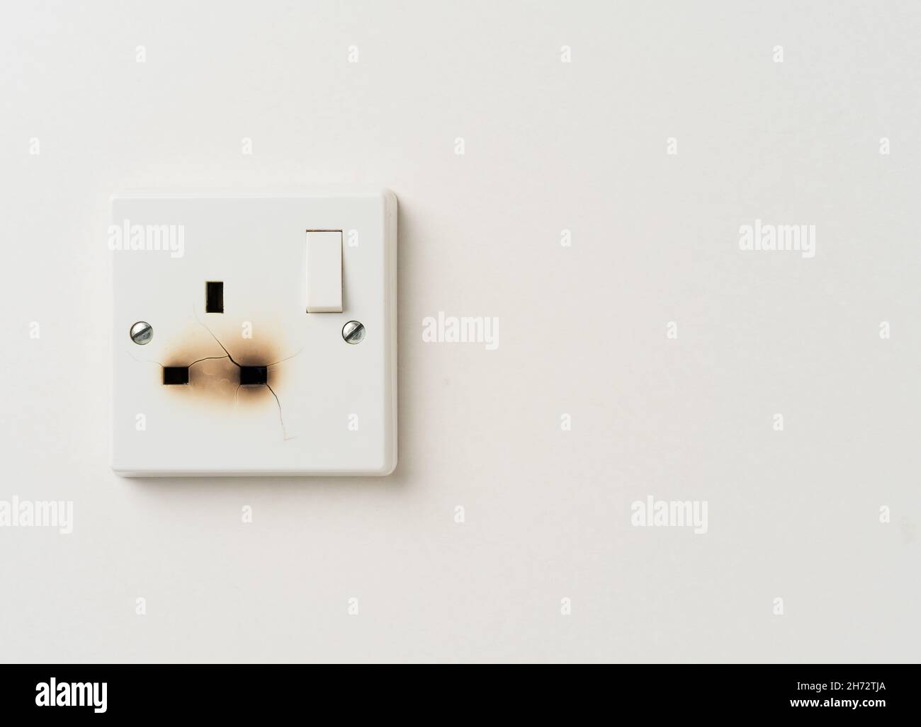 Fire damaged electrical power socket with copy space Stock Photo