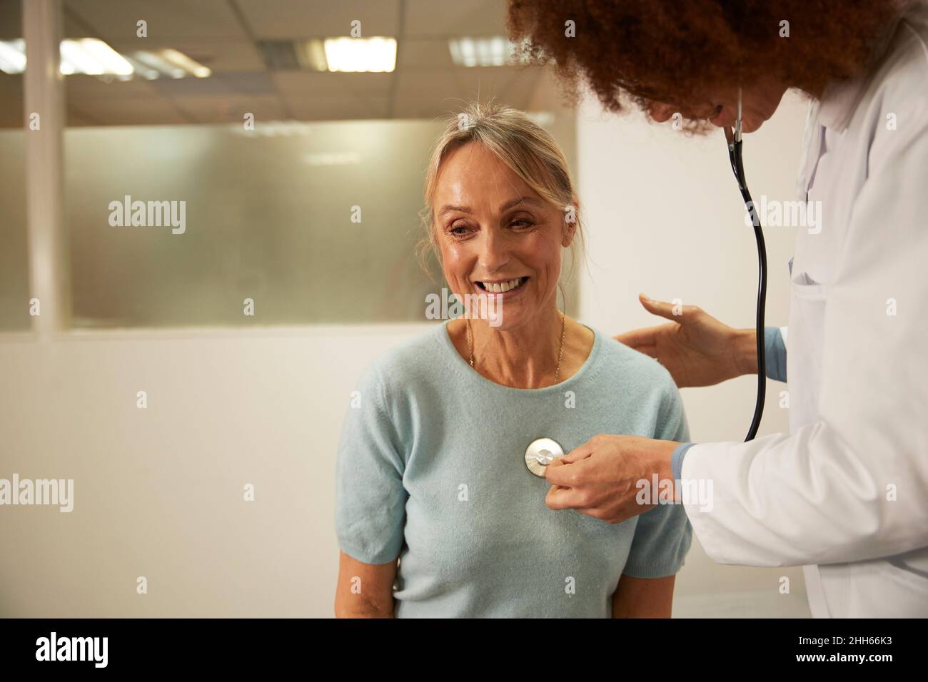 Doctor listening to heartbeat of senior patient in medical room at hospital Stock Photo