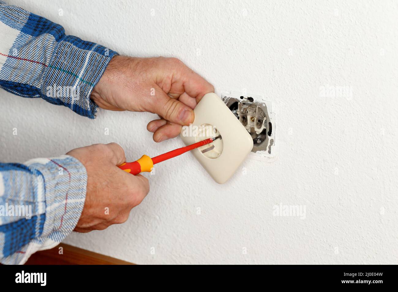 Worker is mounting an electrical socket into a wall Stock Photo