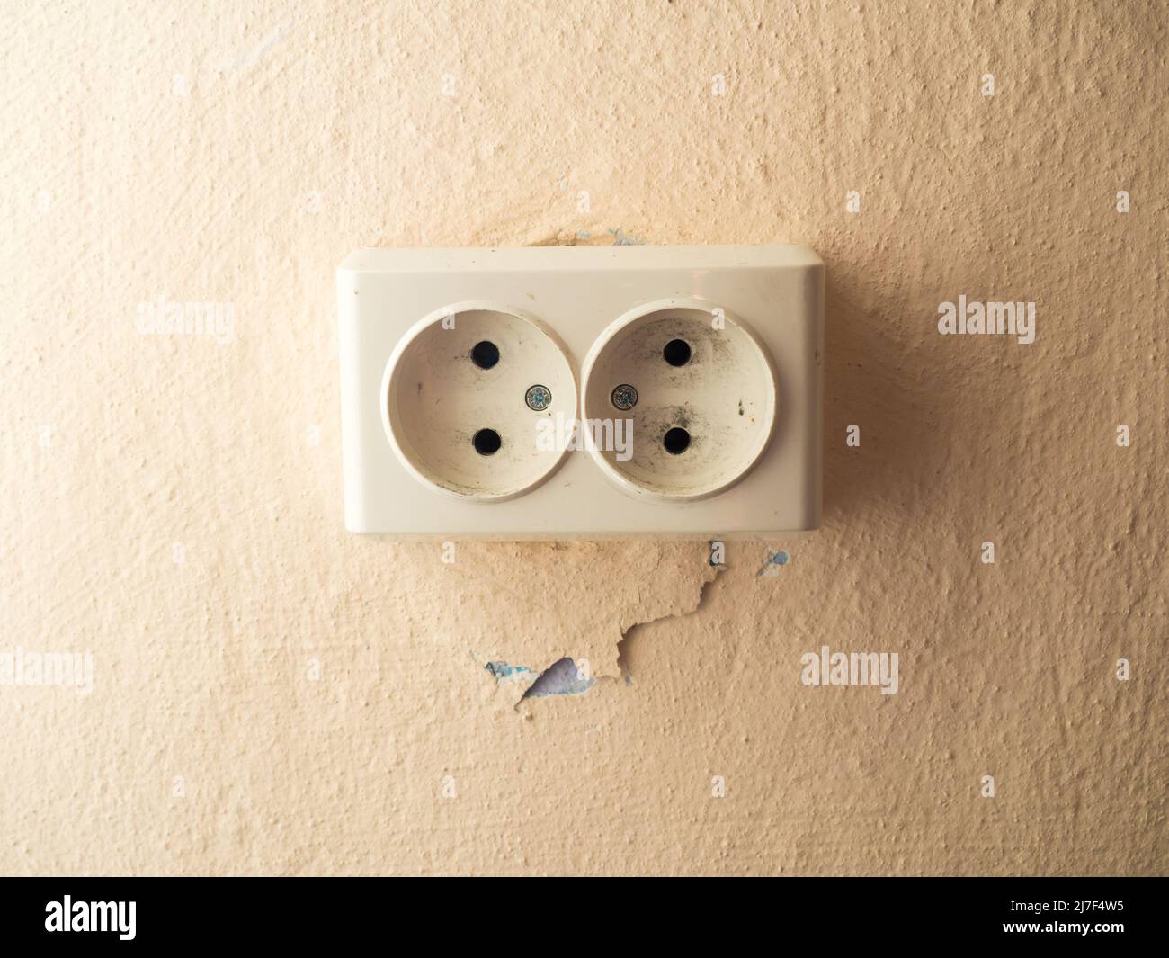 Double socket on the wall with a crack near it Stock Photo