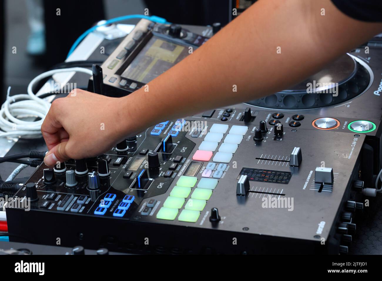 A party DJ turns a knob on a Pioneer DJM-S9 digital mixing board to adjust the 'Hi' notes on a music track at a dance party Stock Photo