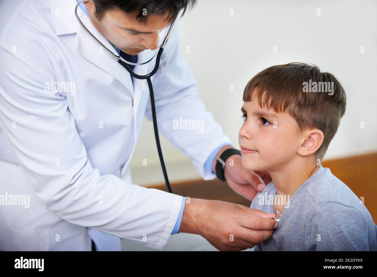 Putting on a brave face. Cropped shot of a doctor listening to his patients heartbeat. Stock Photo