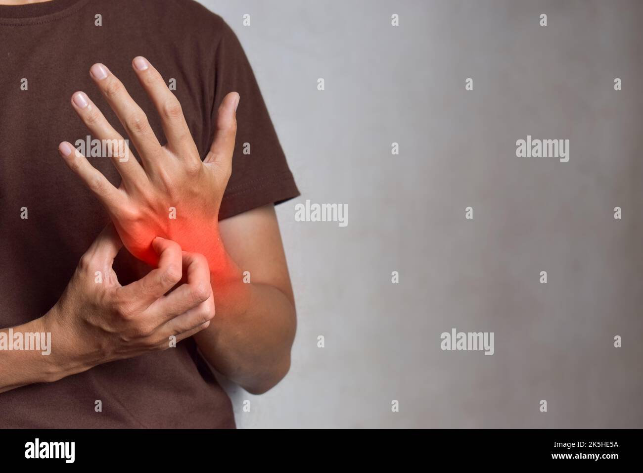 Asian young man scratching his hand. Concept of itchy skin diseases such as scabies, fungal infection, eczema, psoriasis, rash, allergy, etc. Stock Photo