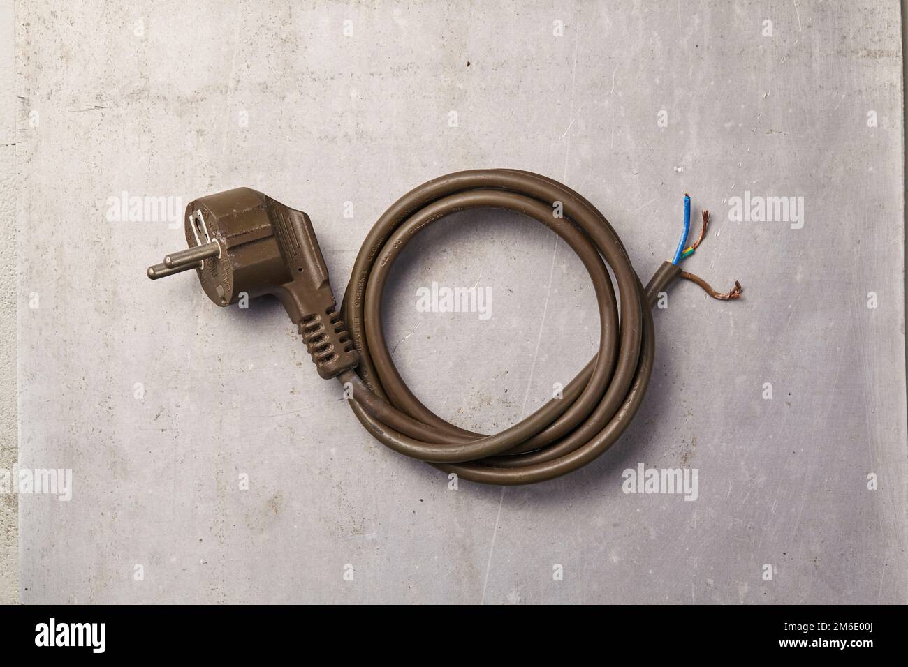 a used and broken power outlet with its wires neatly coiled lying on the floor Stock Photo