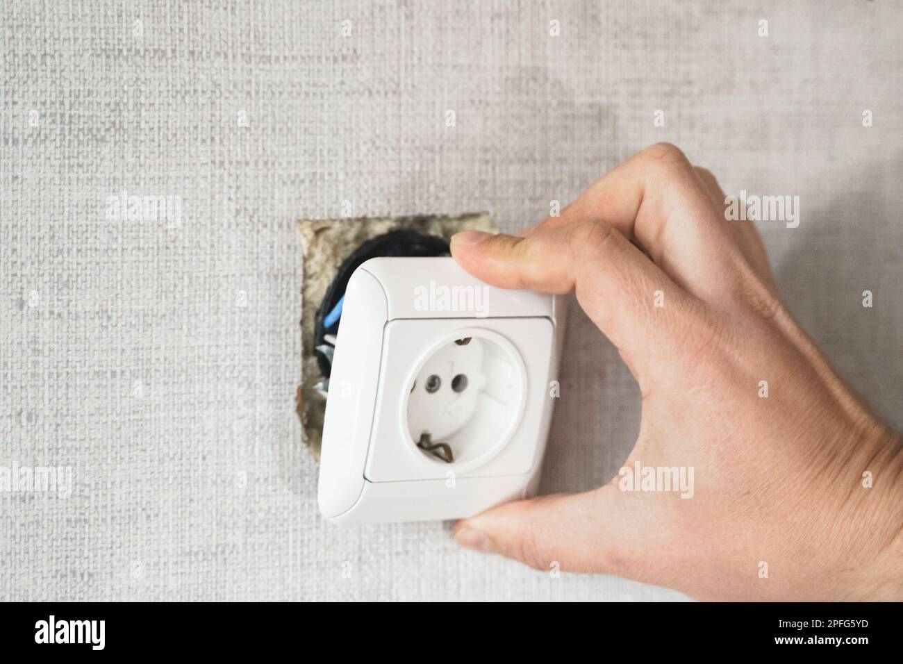 Dangerous bad,broken socket,plug in bathroom,falling out of wall. Outlet installation in old apartment. Poor electrical wire,repair.Terrible do-it-you Stock Photo