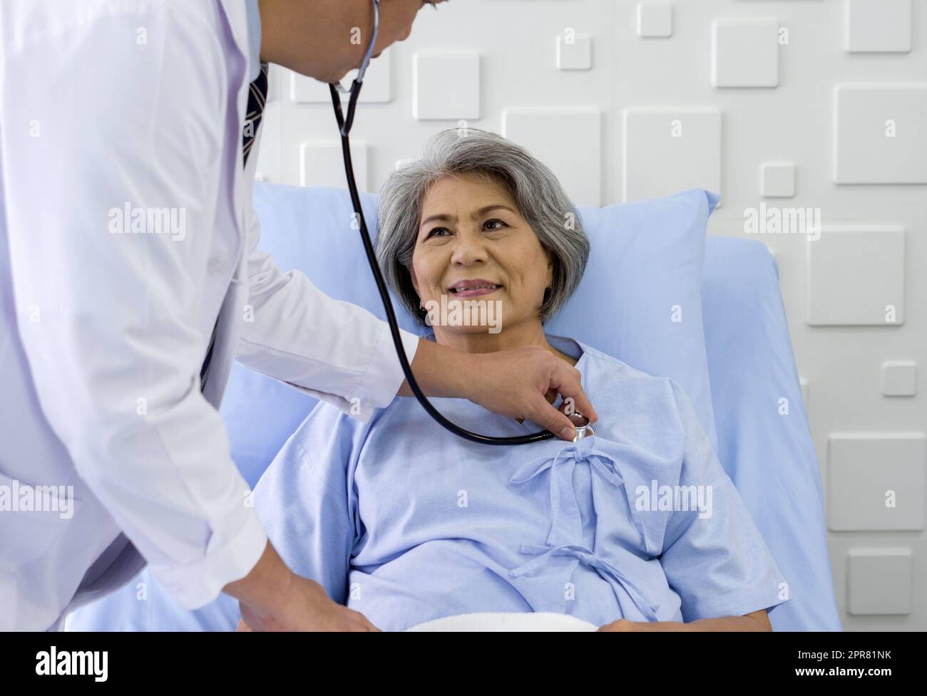 Senior female patient and doctor. Asian doctor use a stethoscope to check the heartbeat of the elderly patient. Stock Photo