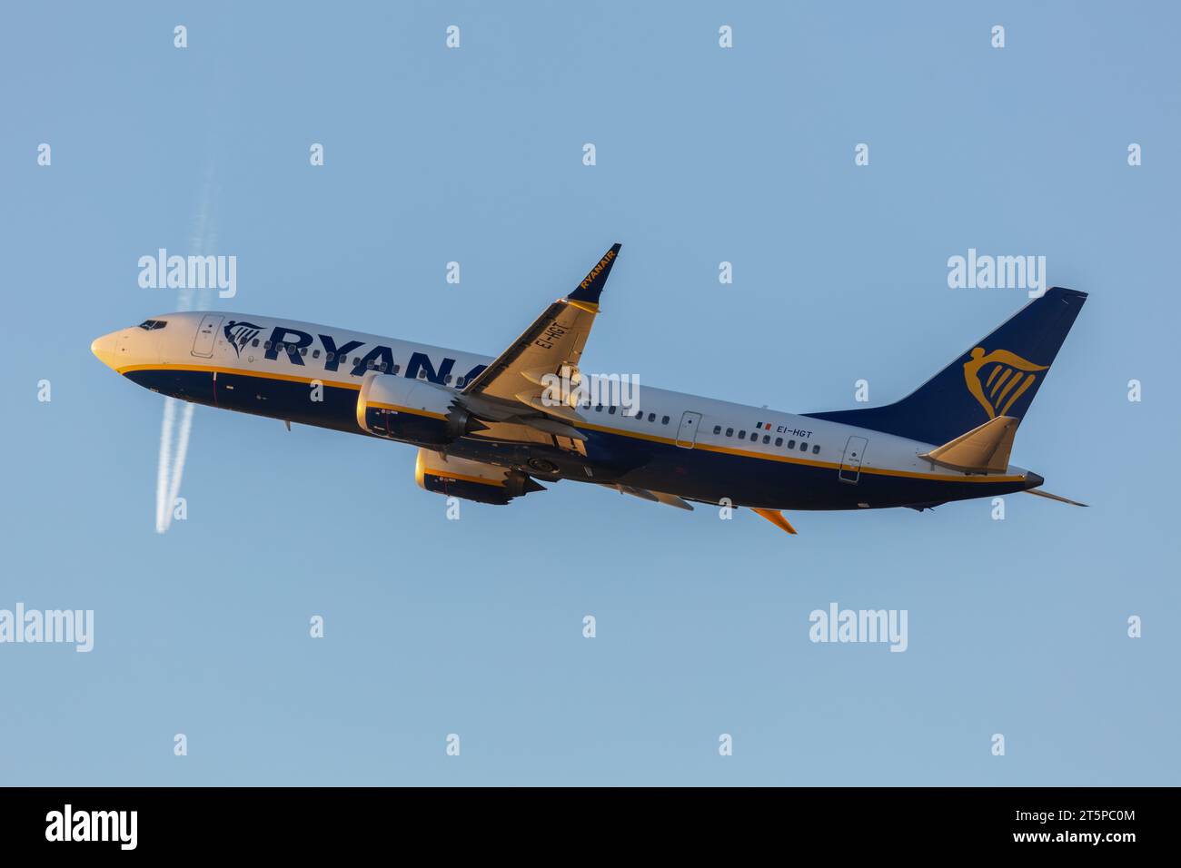 A Ryanair Boeing 737-8 Max, registration EI-HGT departing out of Manchester (MAN) on an evening with the contrails of another aircraft in the distance Stock Photo