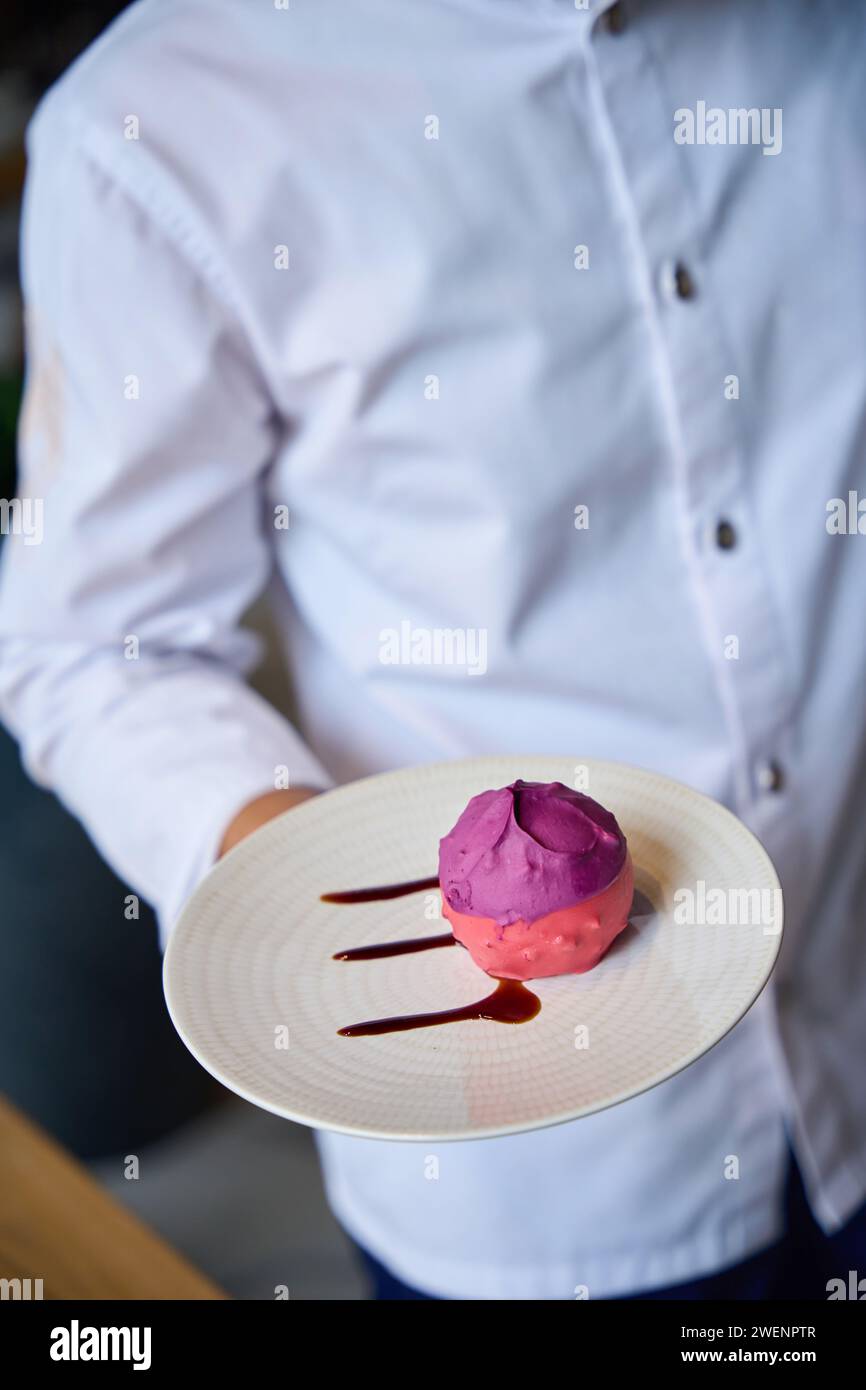 Restaurant kitchen employee presents a pink cake Stock Photo