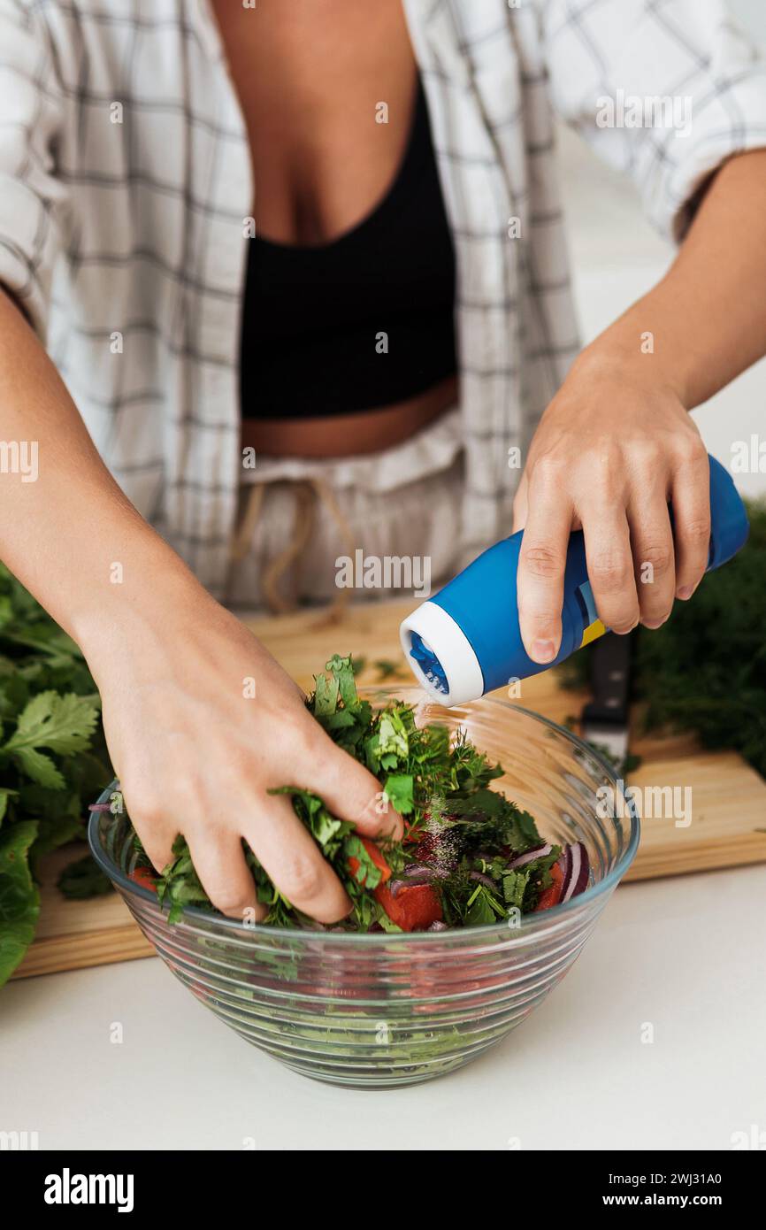 Female hands mixing vegetarian salad and adding the salt to it Stock Photo