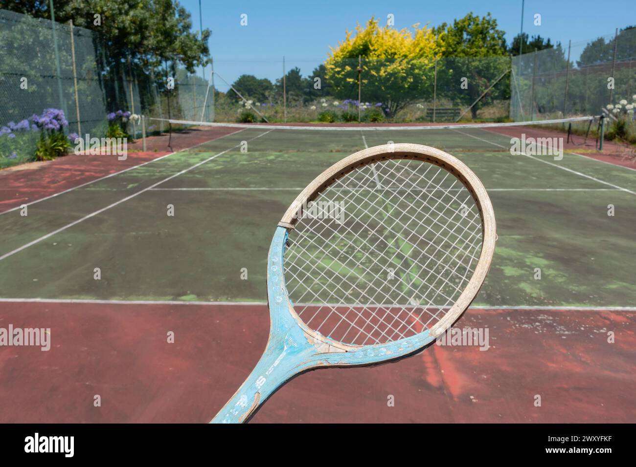 Old wooden tennis racket with neglected tennis court in the background,Bairnsdale ,Victoria, Australia Stock Photo