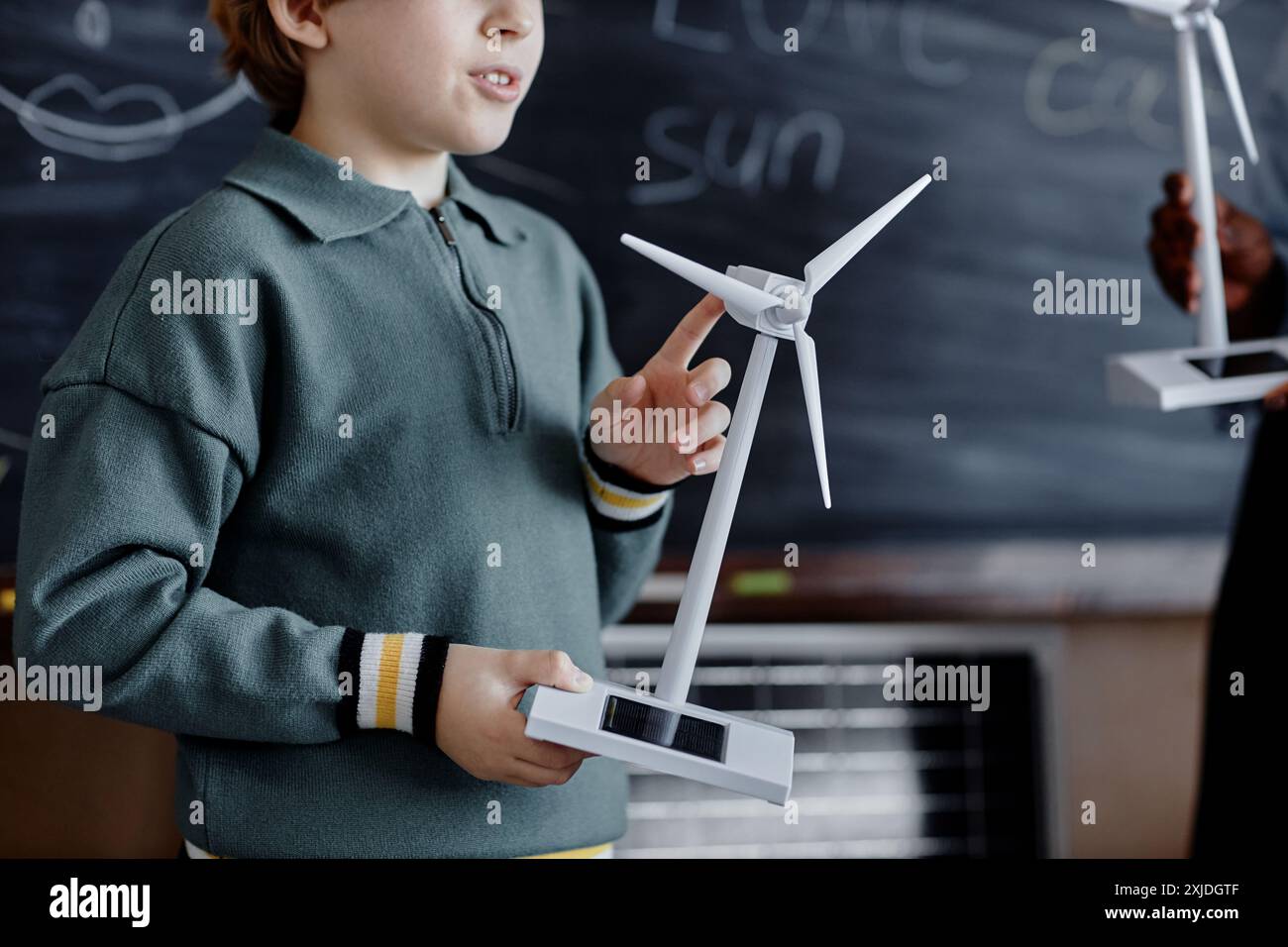 Cropped shot of primary school male student telling class about green energy while holding mini solar powered small wind turbine Stock Photo