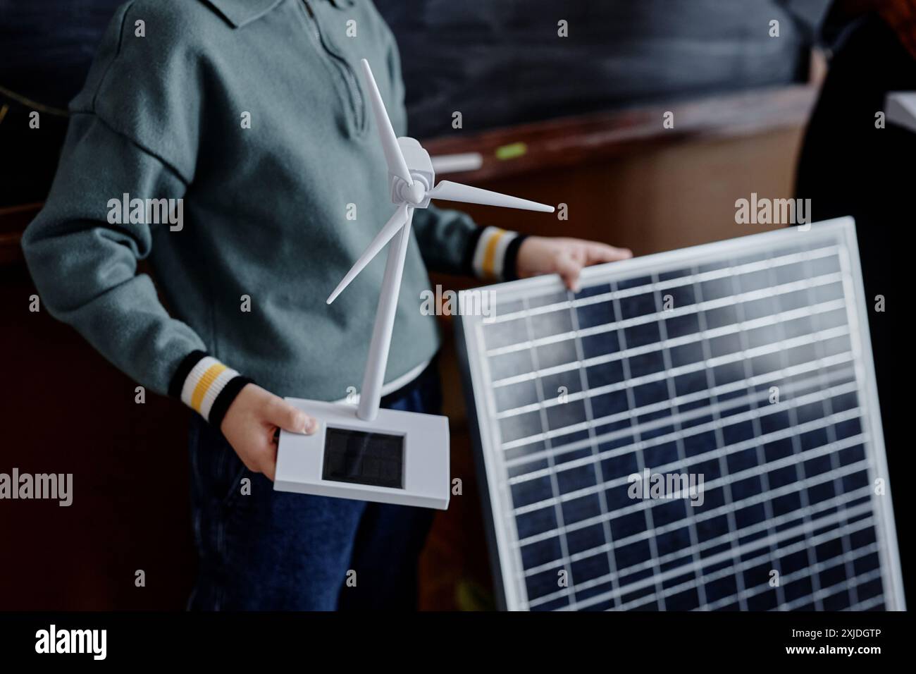 Close up on mini solar energy wind turbine and huge solar panel in hands of primary schoolboy presenting project about sustainable technology in class, copy space Stock Photo