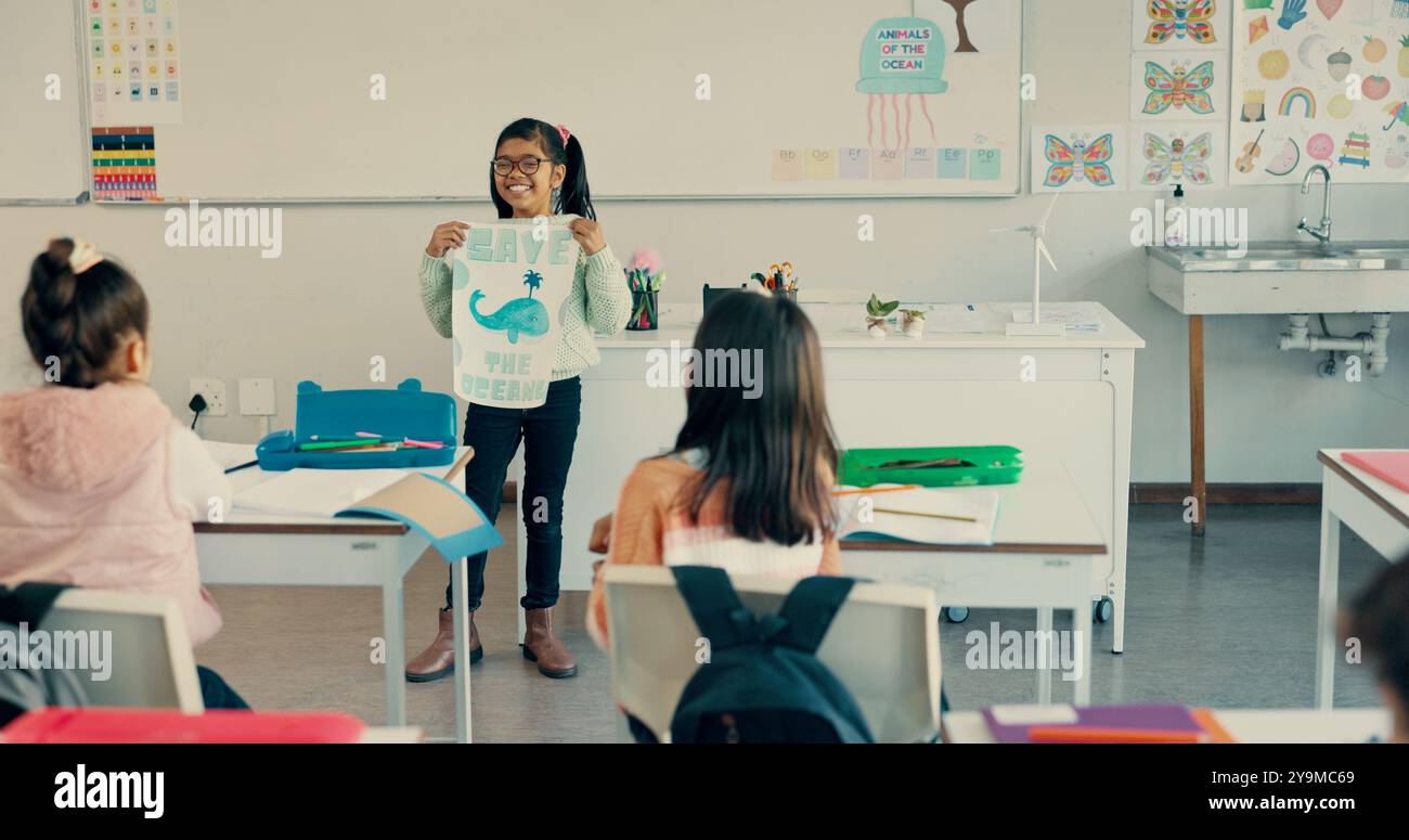 Happy girl, classroom and presentation with poster for global warming, ocean conservation or awareness at school. Young kid, child or elementary Stock Photo