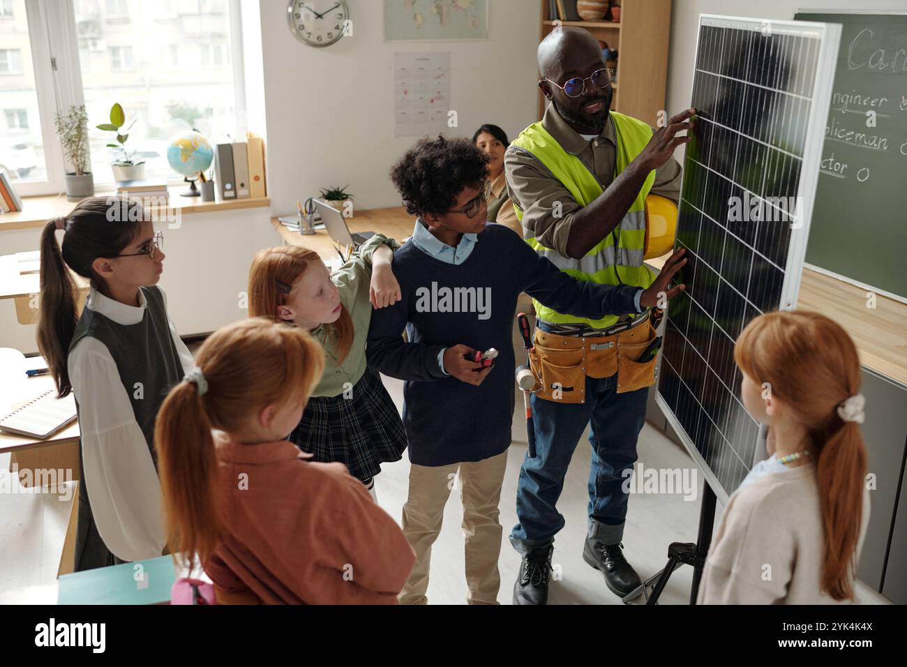 Cute primary schoolboy and professional engineer touching solar panel during presentation of renewable sources of energy Stock Photo