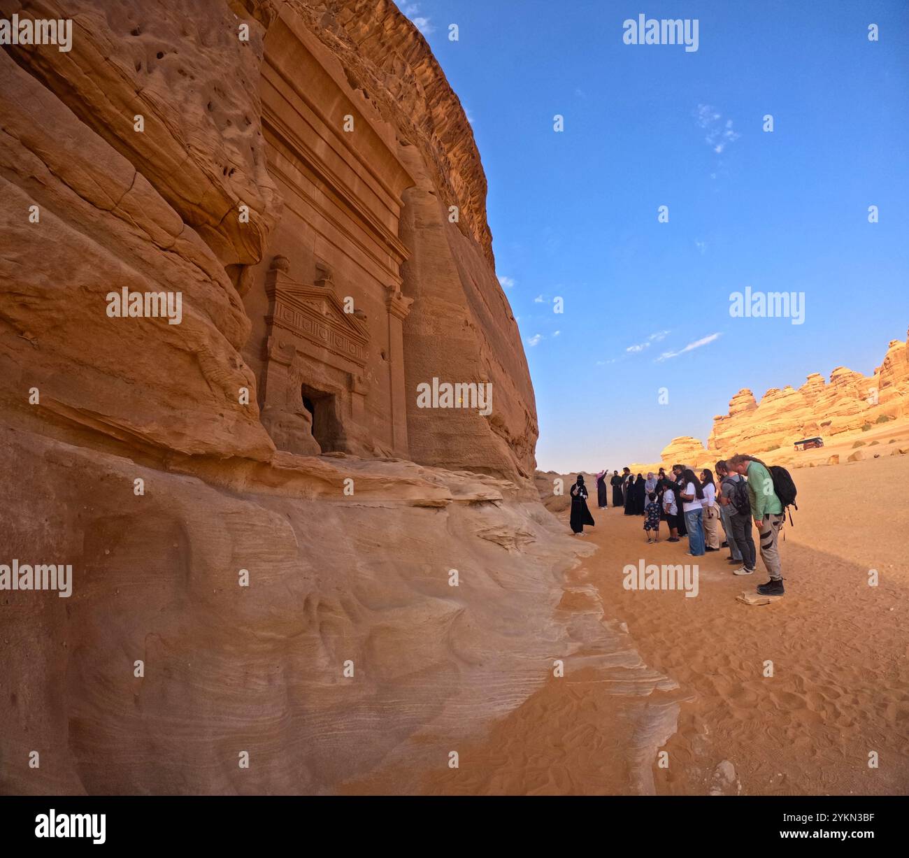 Tourists viewing tomb 45 at Jabal AlBanat (Qasr AlBint), Hegra Archaeological Site (al-Hijr / Madā ͐ in Ṣāliḥ), in the desert near Al Ula, Saudi Arabi Stock Photo