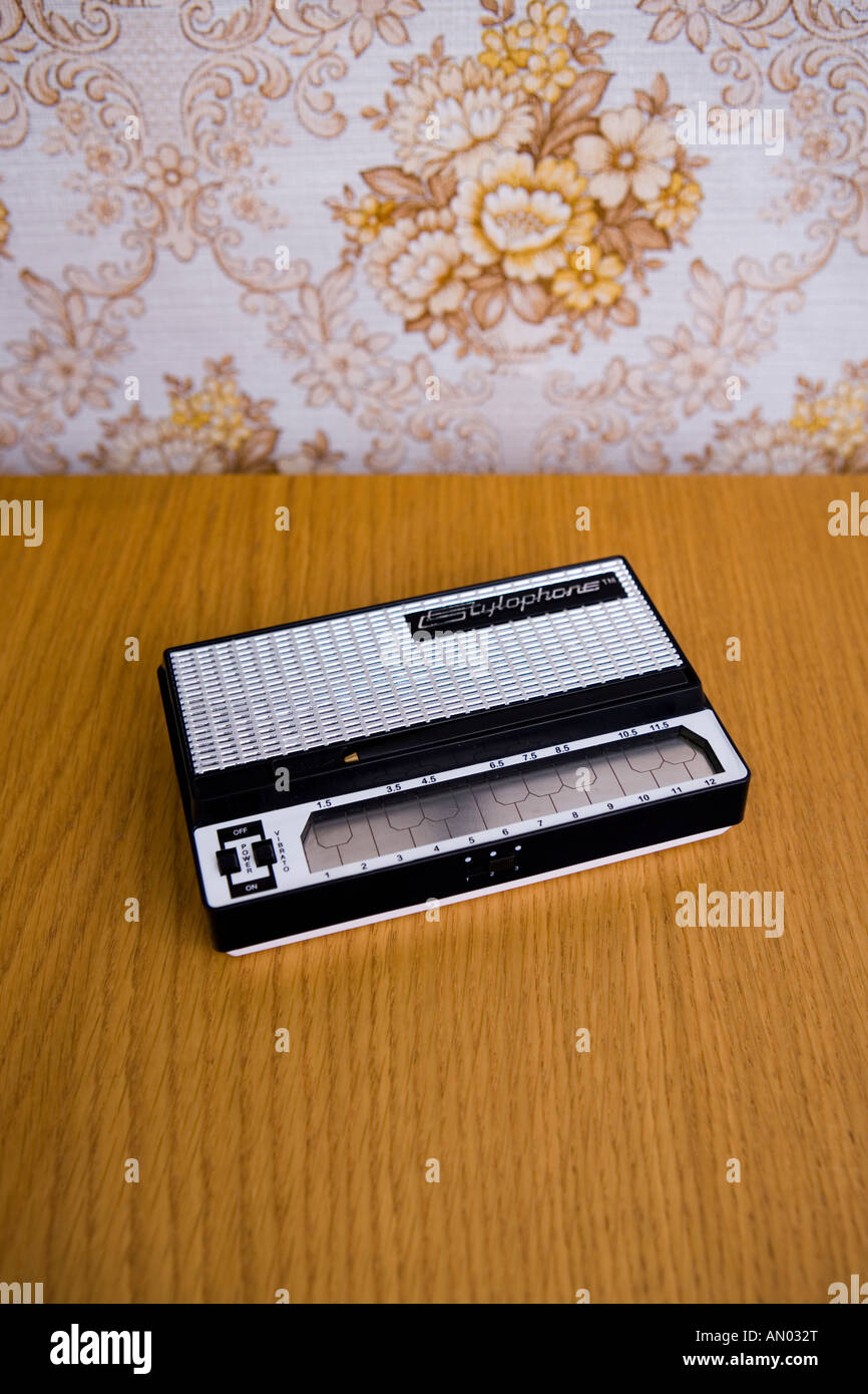 Original vintage stylophone on woooden table with kitsch 1970's wallpaper backdrop Stock Photo