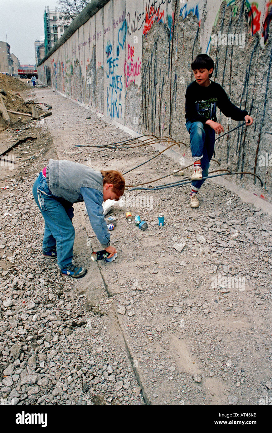 The Fall of the Berlin wall, 1989. A children spray paint rocks to sell as genuine graffiti from the wall. Stock Photo