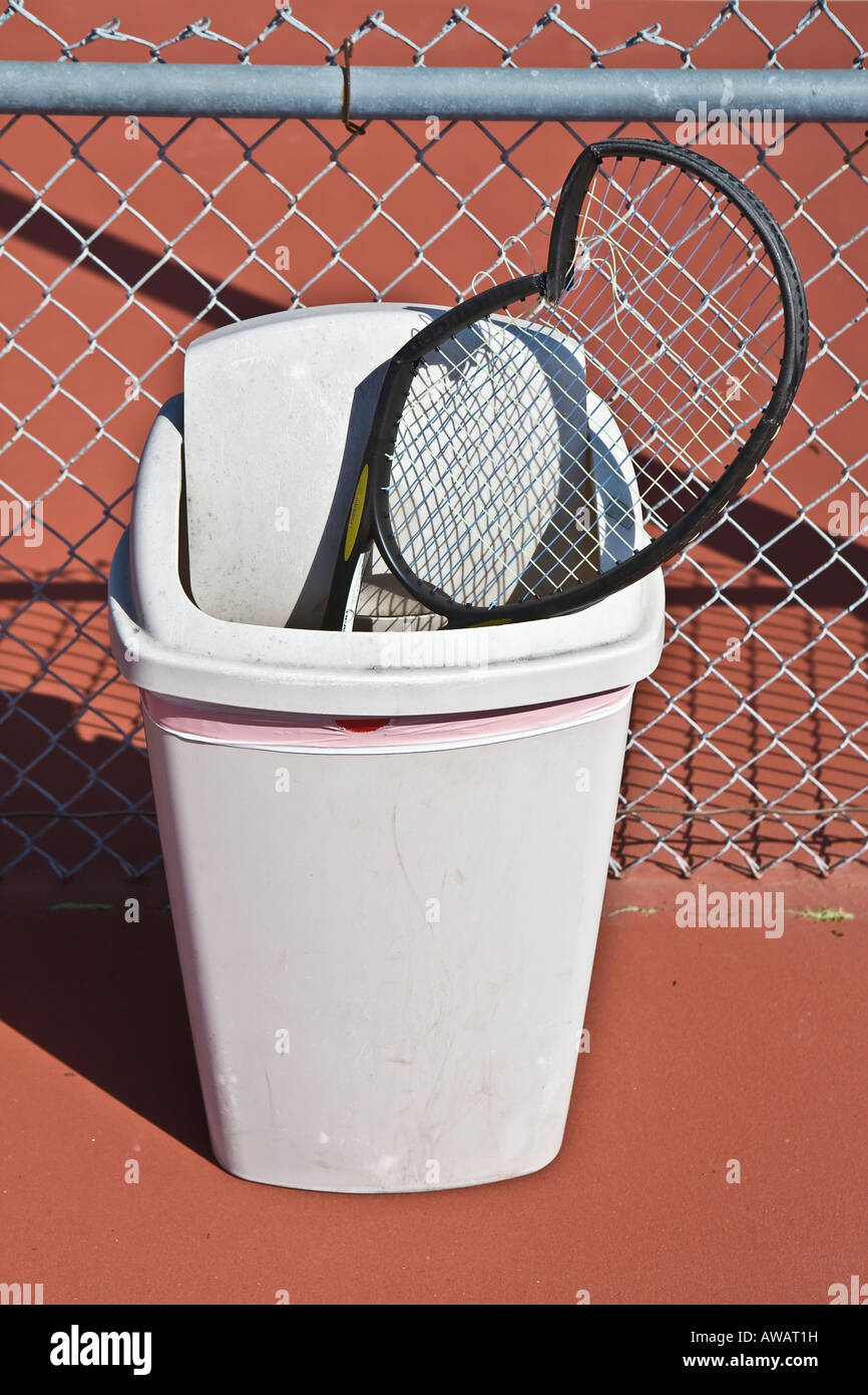 Broken tennis racket in trash receptacle on court Stock Photo