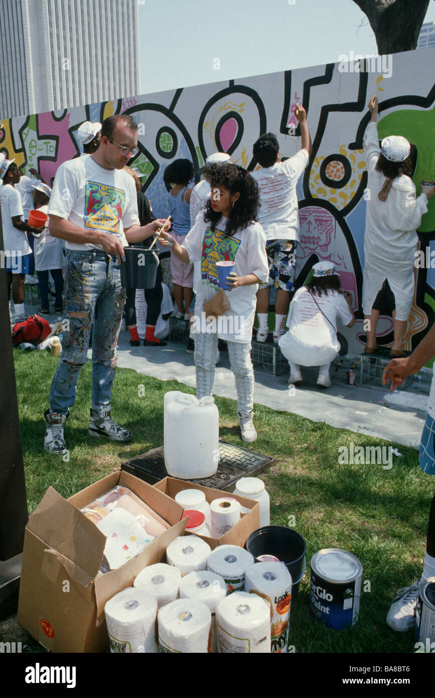 Teens in school art program paint in mural figures drawn by late artist Keith Haring (on left) in Grant Park Chicago Illinois Stock Photo