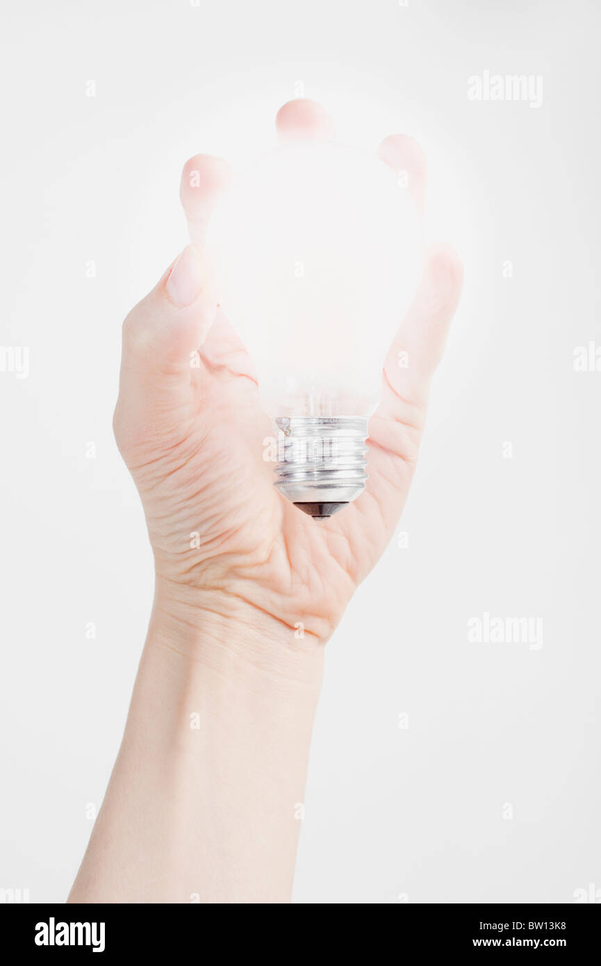 Hand holding a glowing light bulb Stock Photo