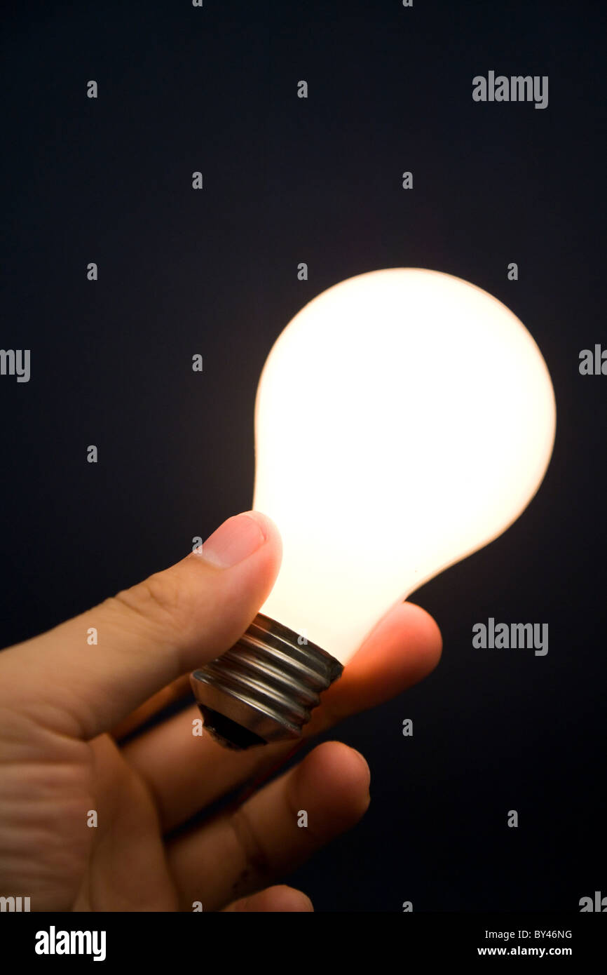 Hand holding a Bright Light Bulb, Concept of Inspiration, Ideas Stock Photo