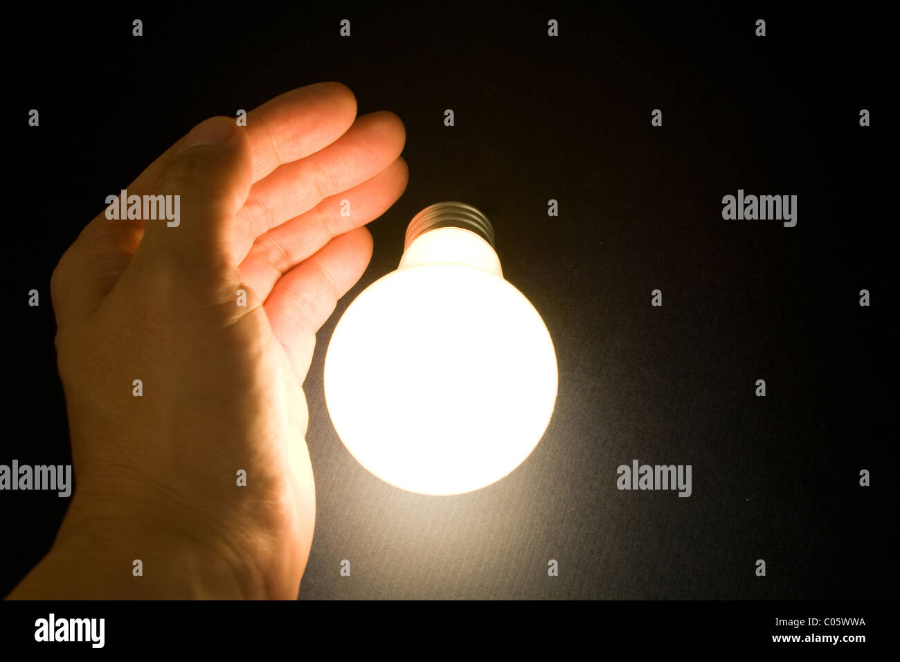 Hand and a Bright Light Bulb, Concept of Inspiration, Ideas Stock Photo