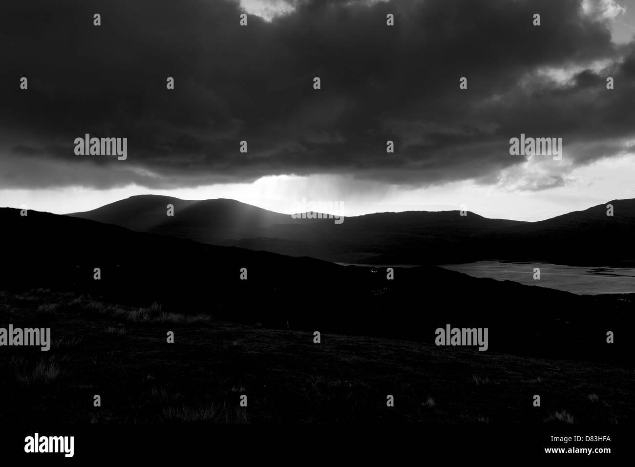 Rainy moody skies with sun poking through clouds over mountains giving hope and change for the future Stock Photo