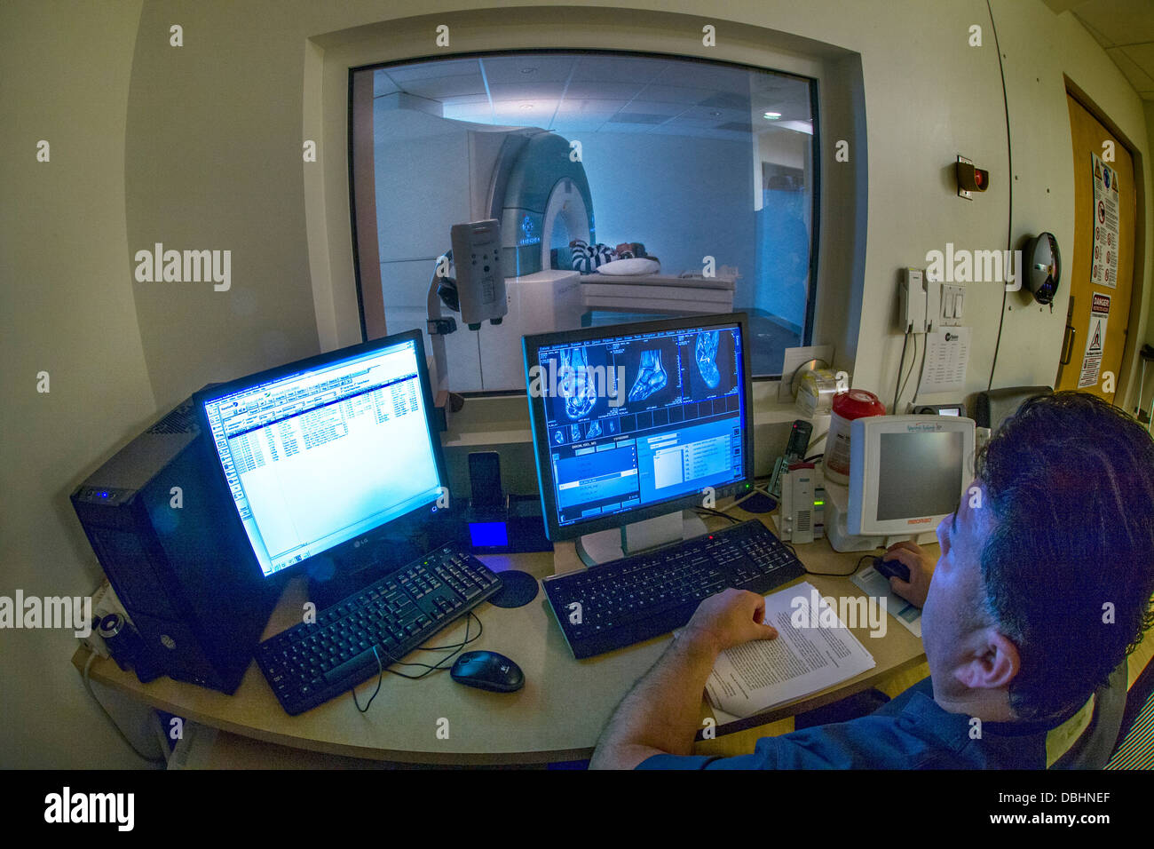 Viewed through safety glass window teenage girll's injured ankle is examined using a Siemens 3T Vario magnetic resonance imaging Stock Photo