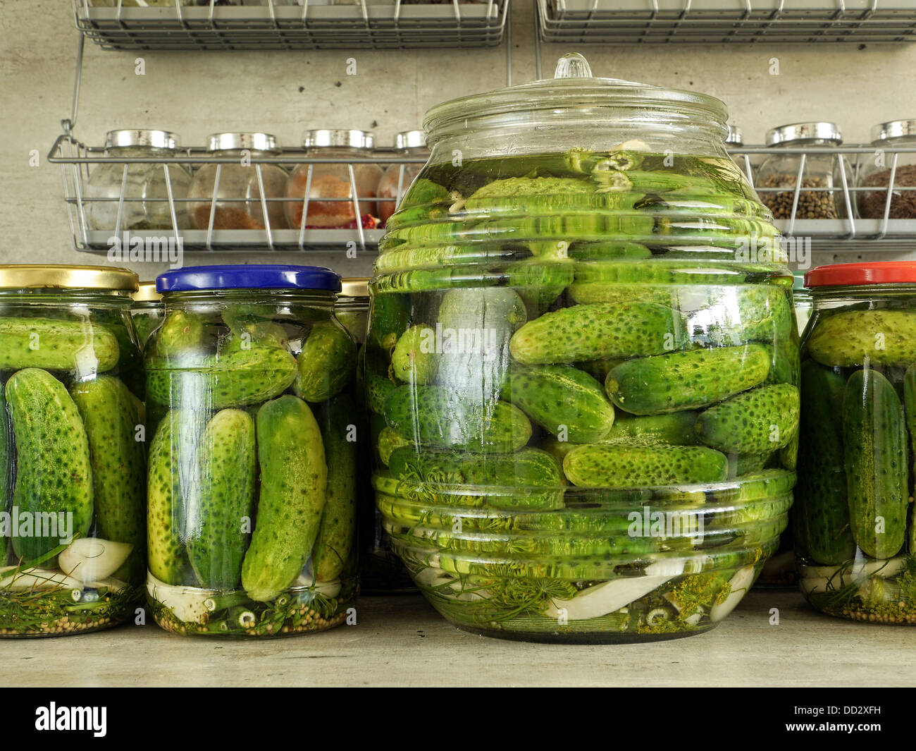 Pickled green cucumbers in glass jars on kitchen countertop Stock Photo