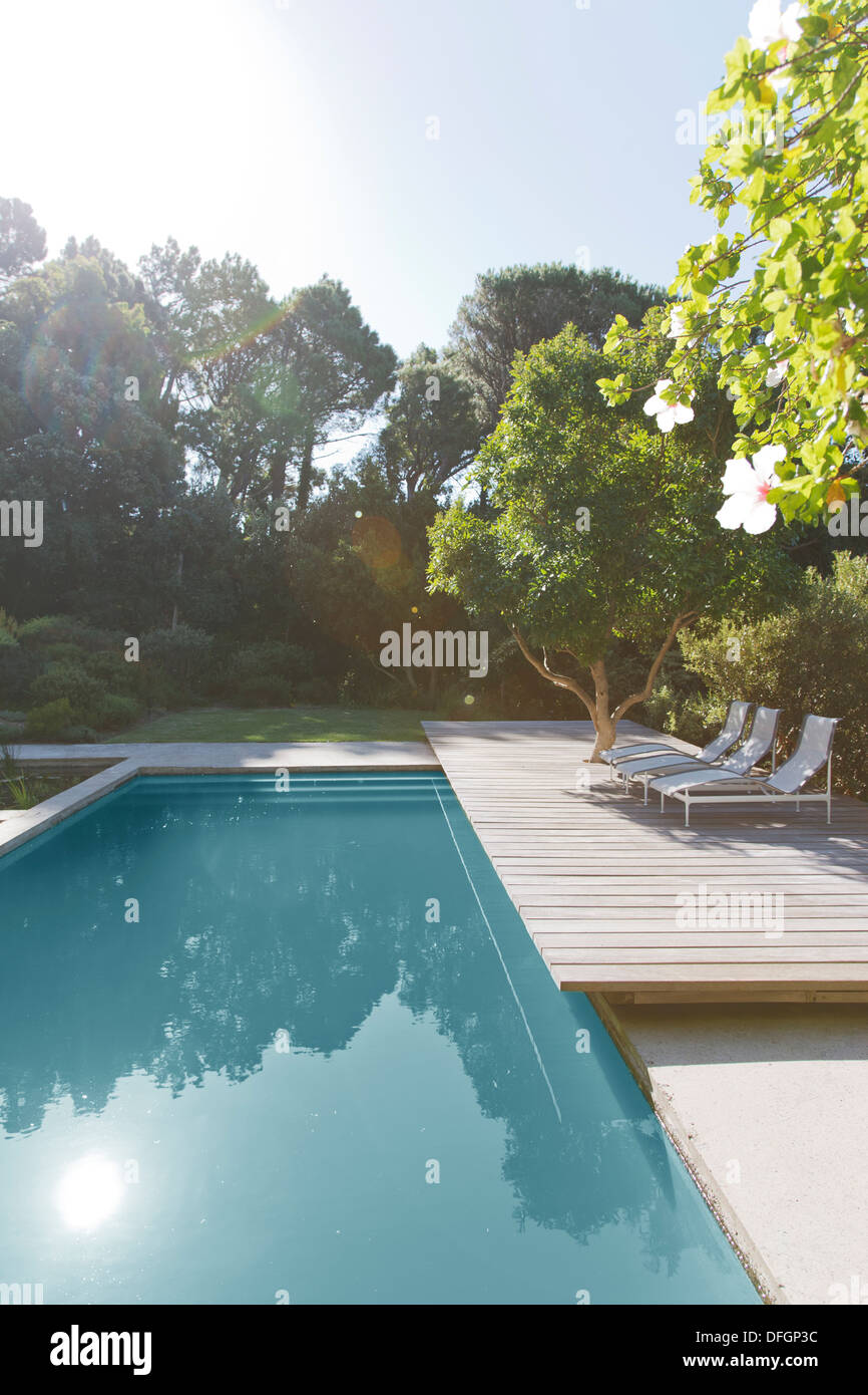 Wooden deck and lounge chairs by swimming pool Stock Photo