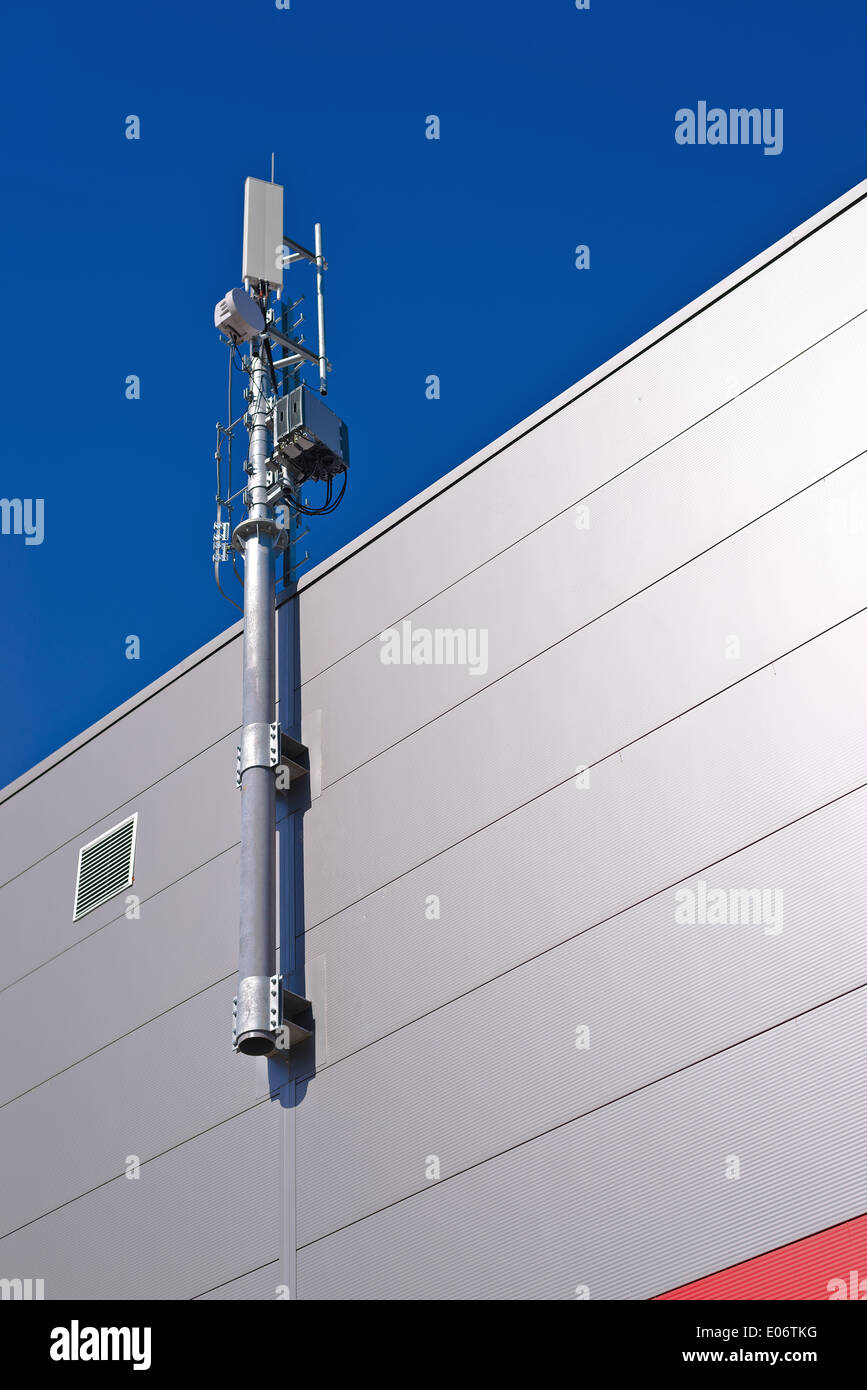 GSM Antenna. Mobile phone signal repeater system installed on the roof top of industrial building. Stock Photo