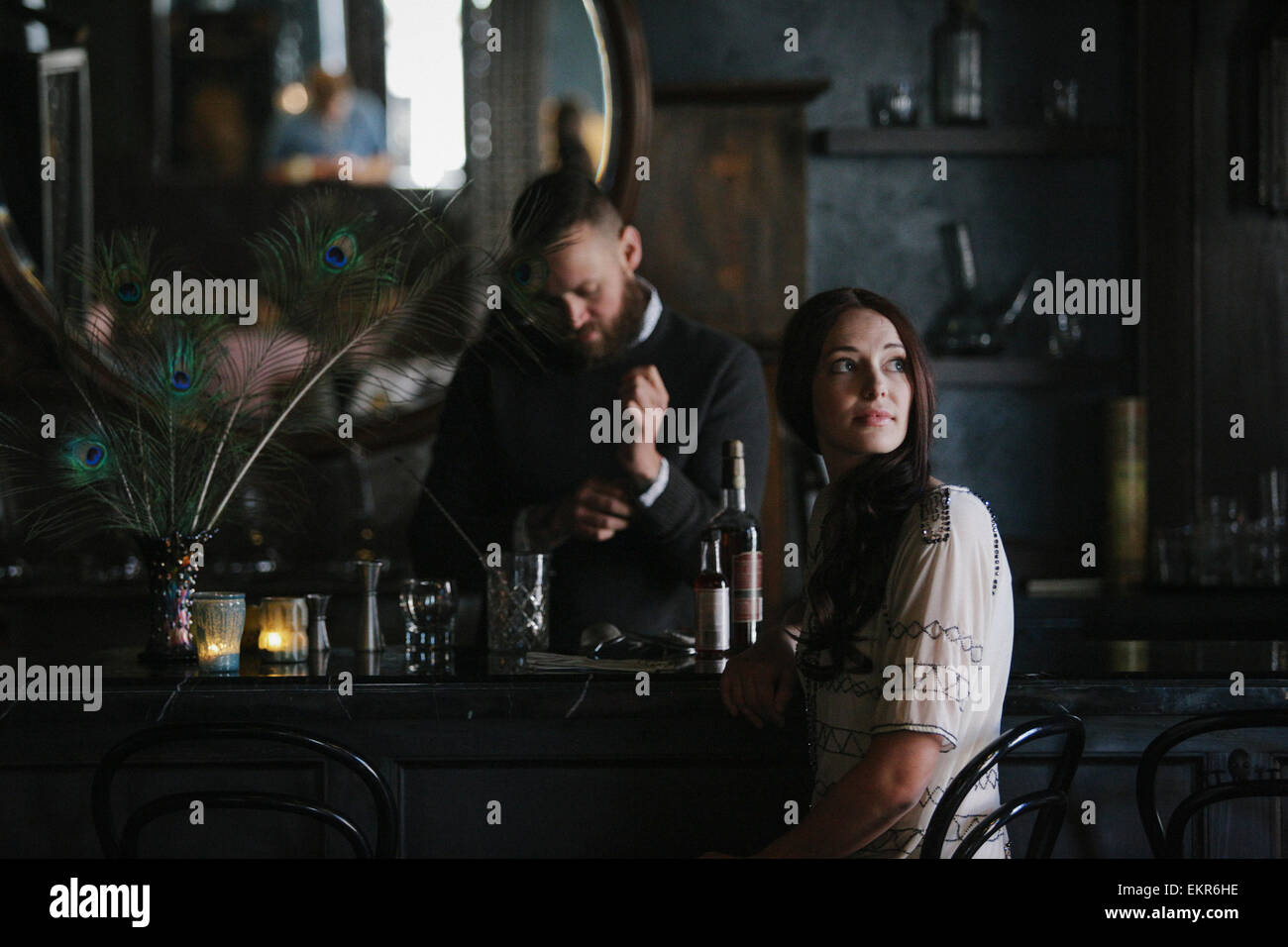 A woman and a bartender talking, and mixing drinks. Stock Photo