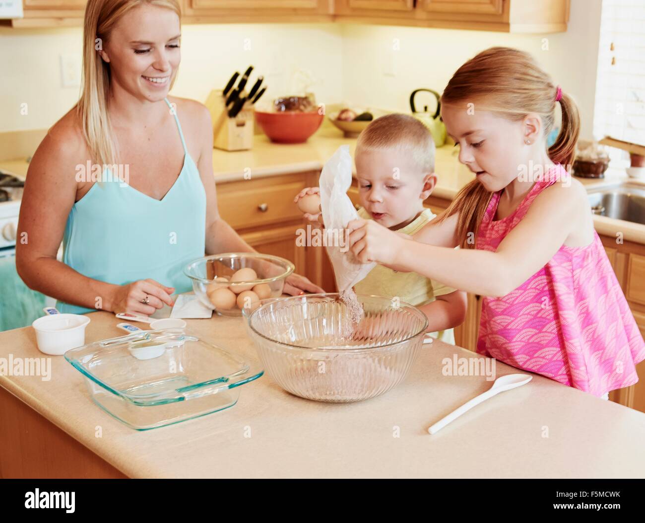 Family preparing batter in mixing bowl Stock Photo