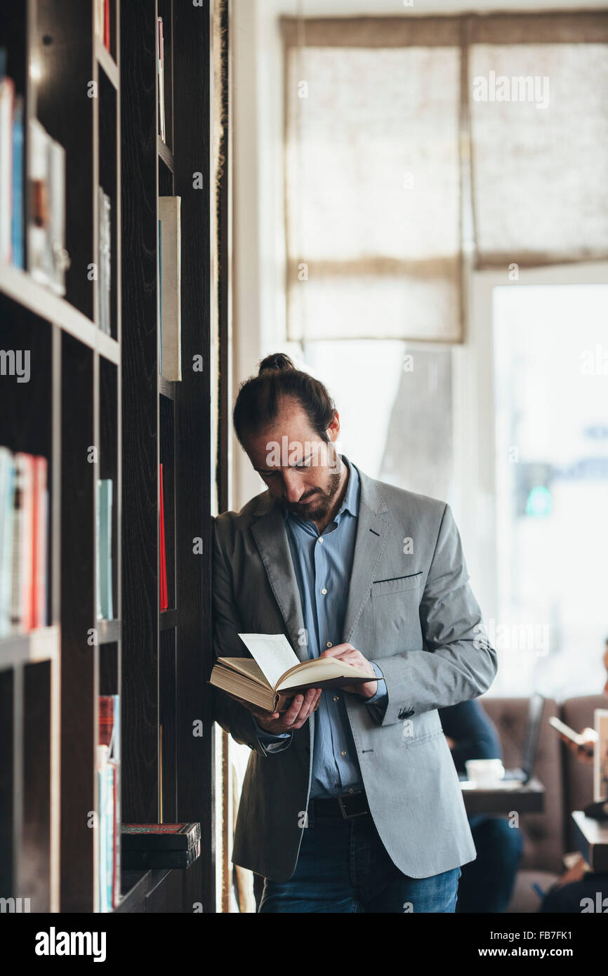 Mid adult businessman reading book in cafe Stock Photo